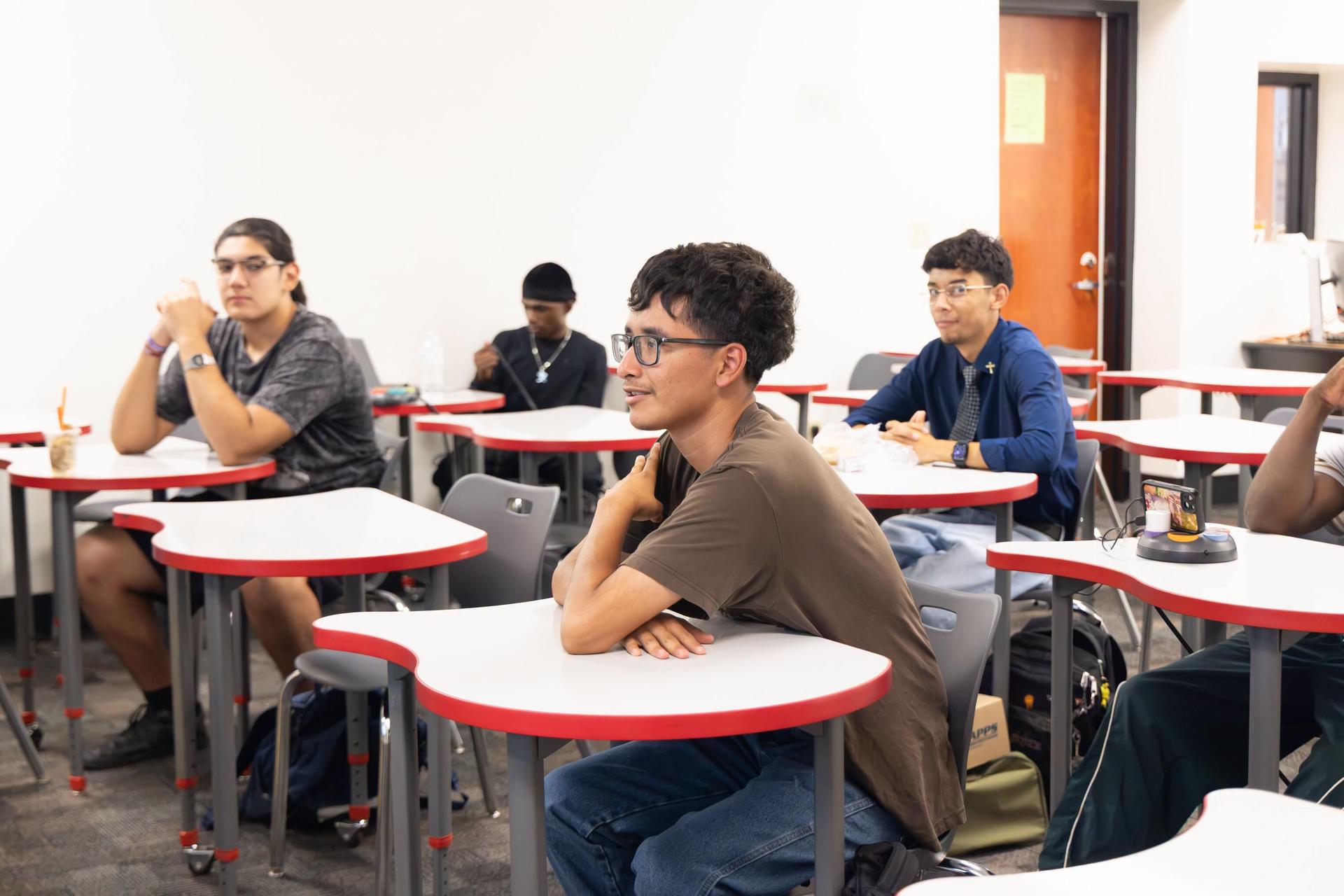 A classroom with students seated at desks, each with a backpack, engaged in an activity.