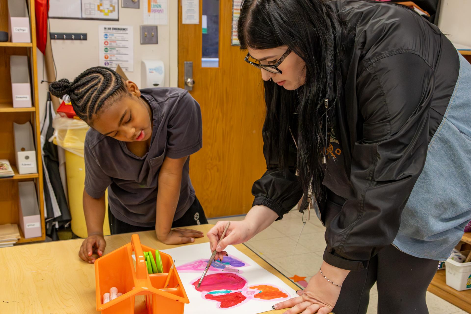 teacher help art student in class