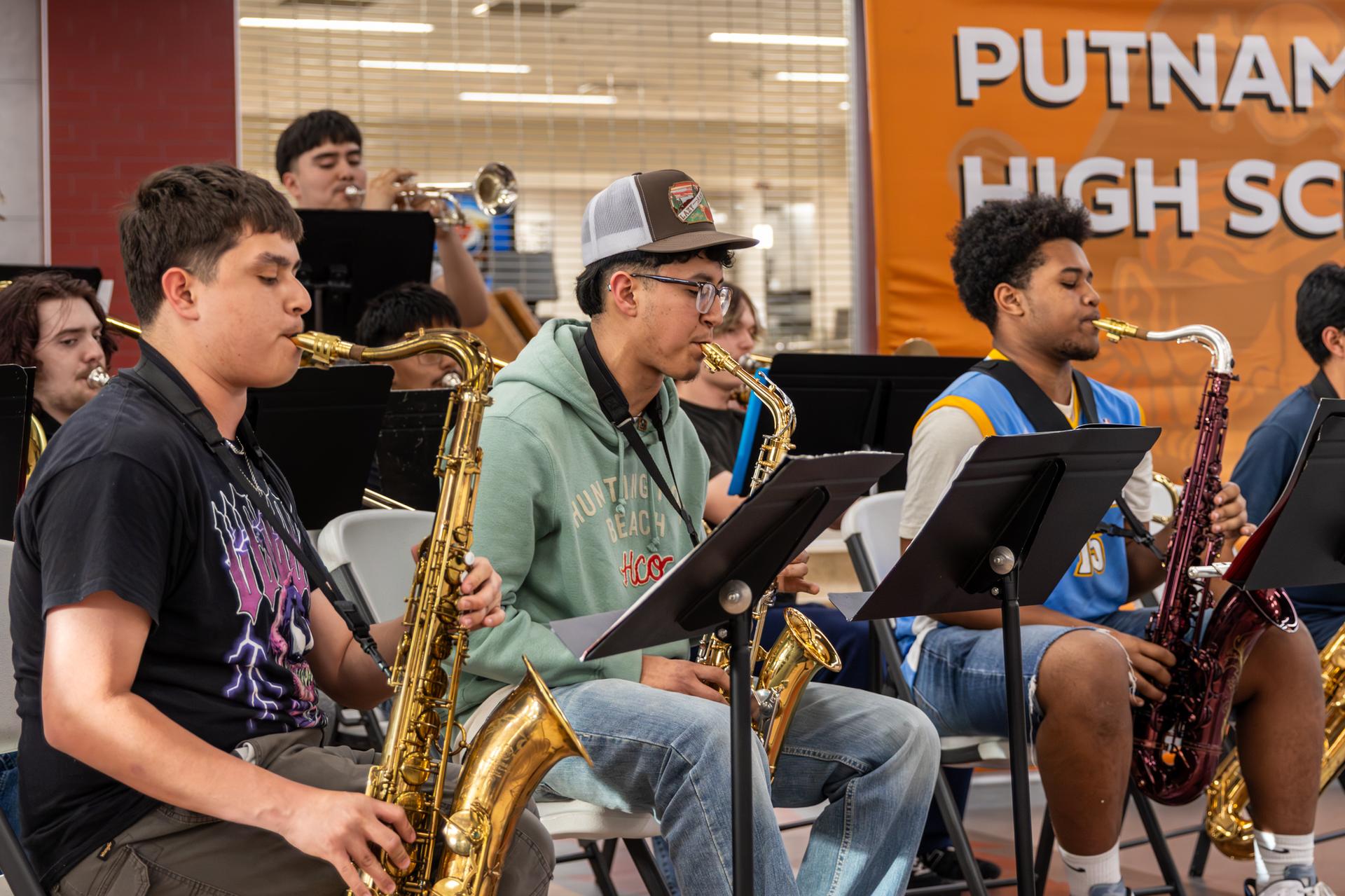 3 male students playing the saxophone 