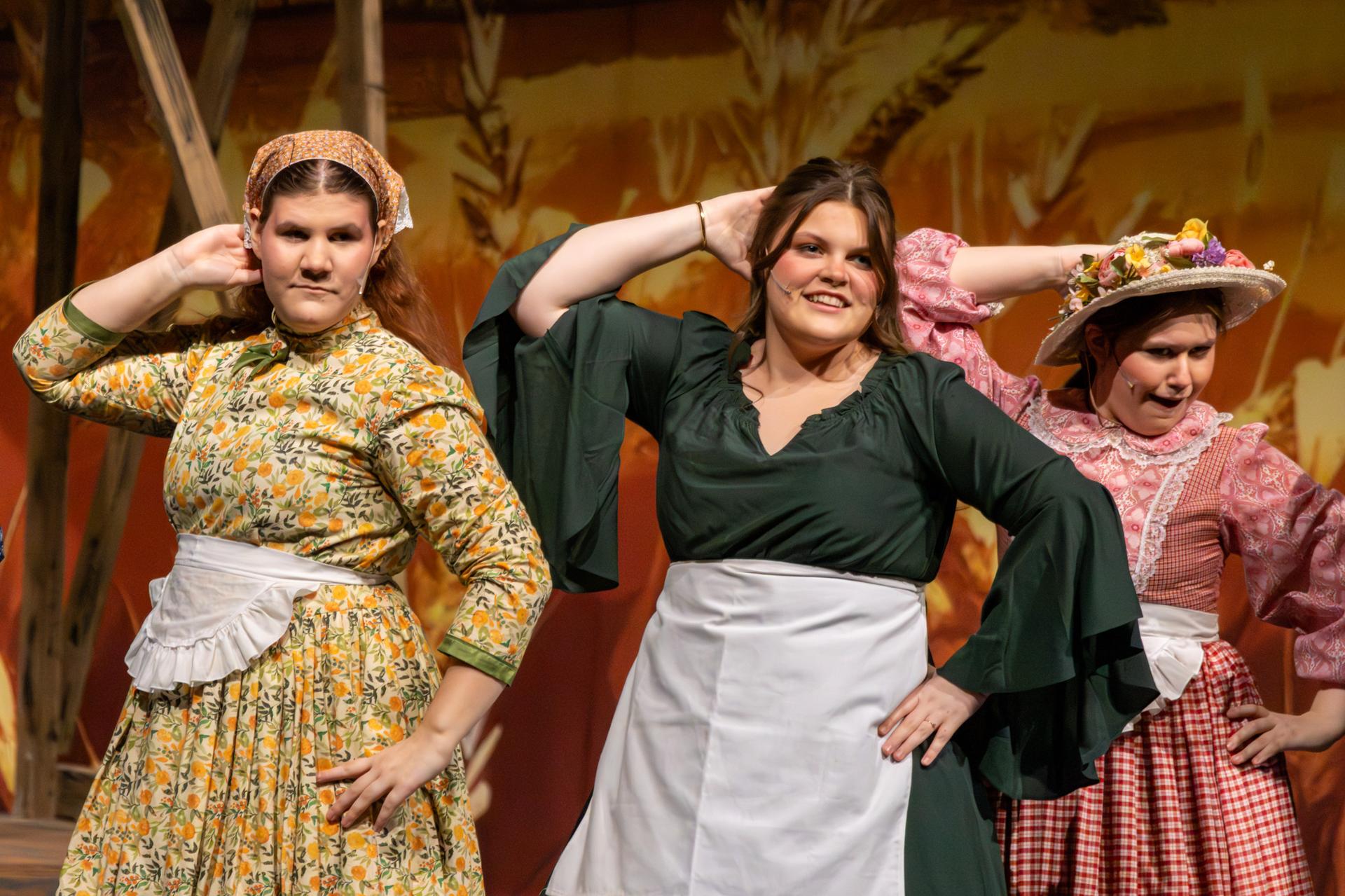 3 performers hand on head singing