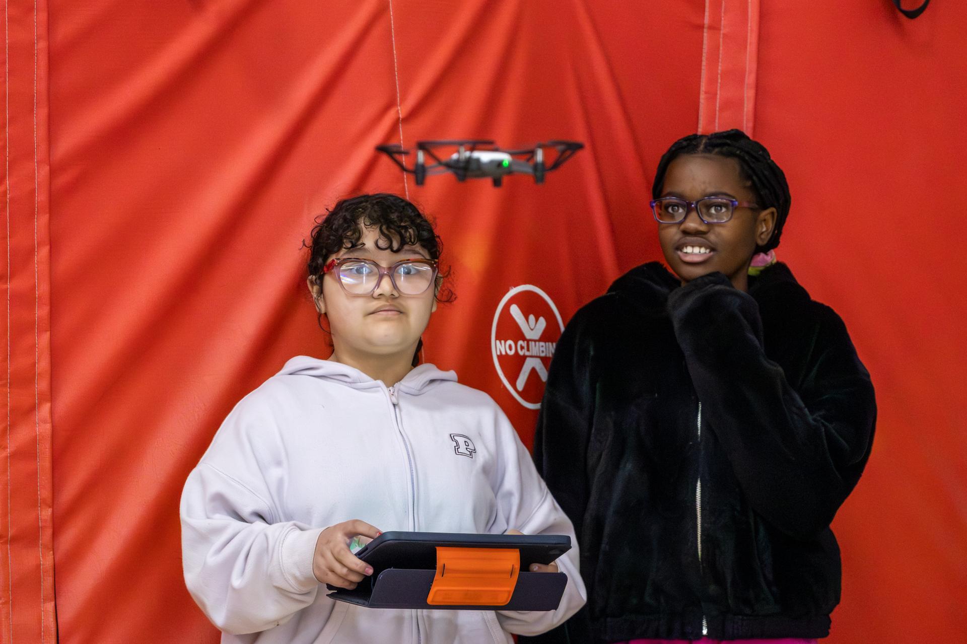 2 female students looking at a drone