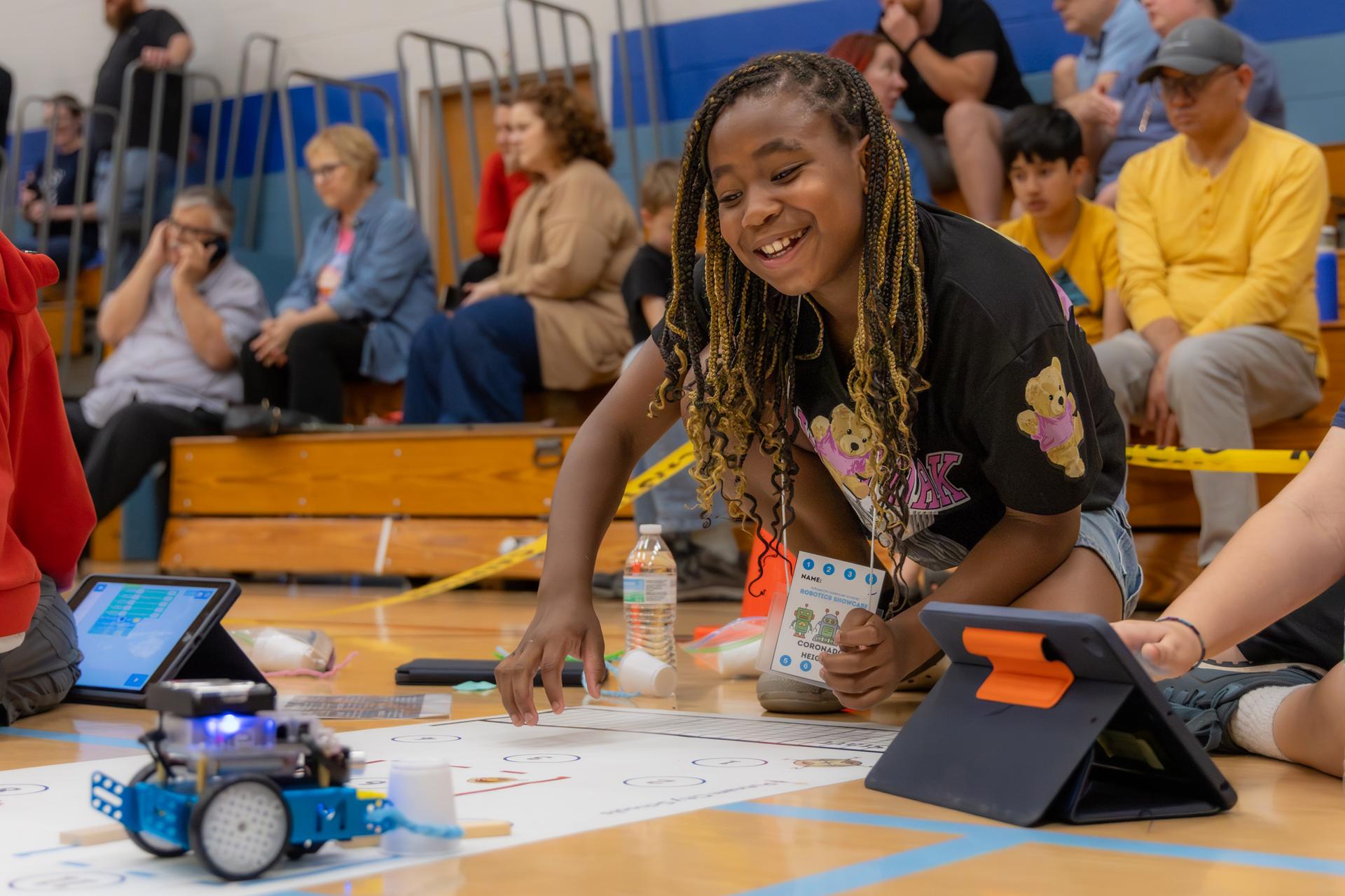 student smiling looking at her robot