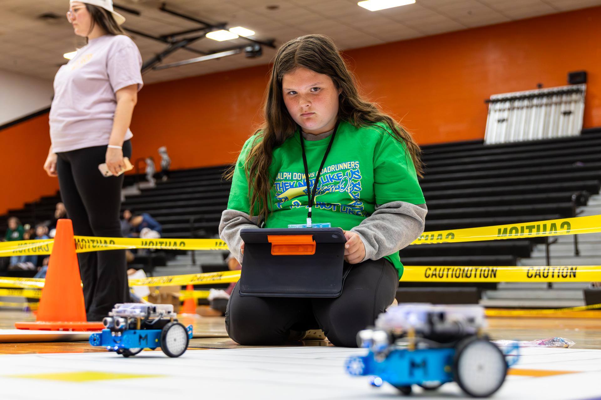 student looking at robot while holding ipad