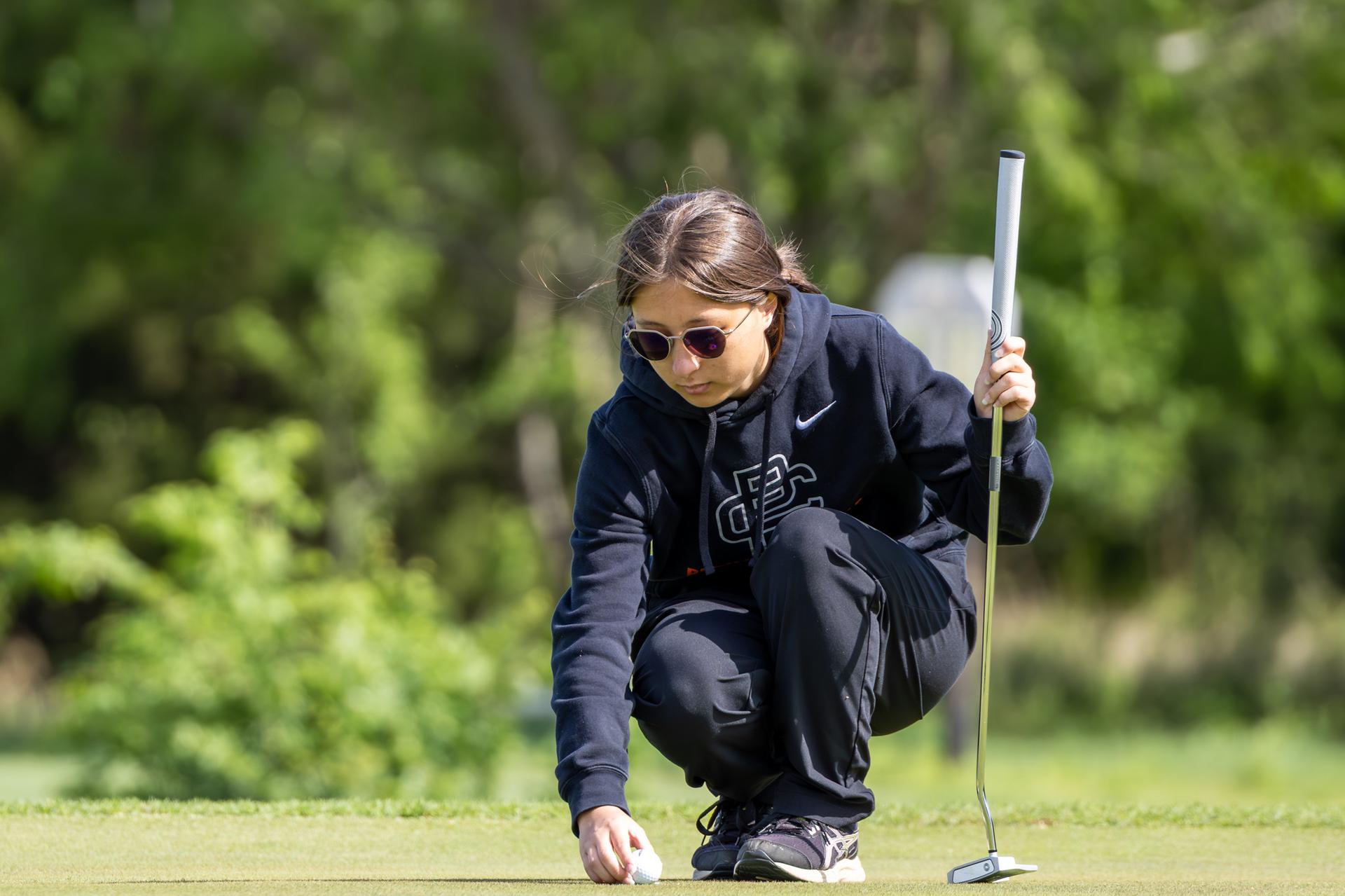 student lining up ball on golf course