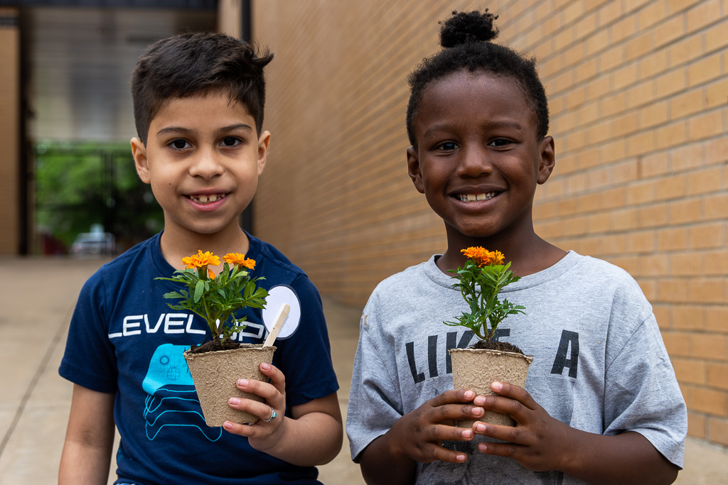 students looking in camera smiling with plants in their hand