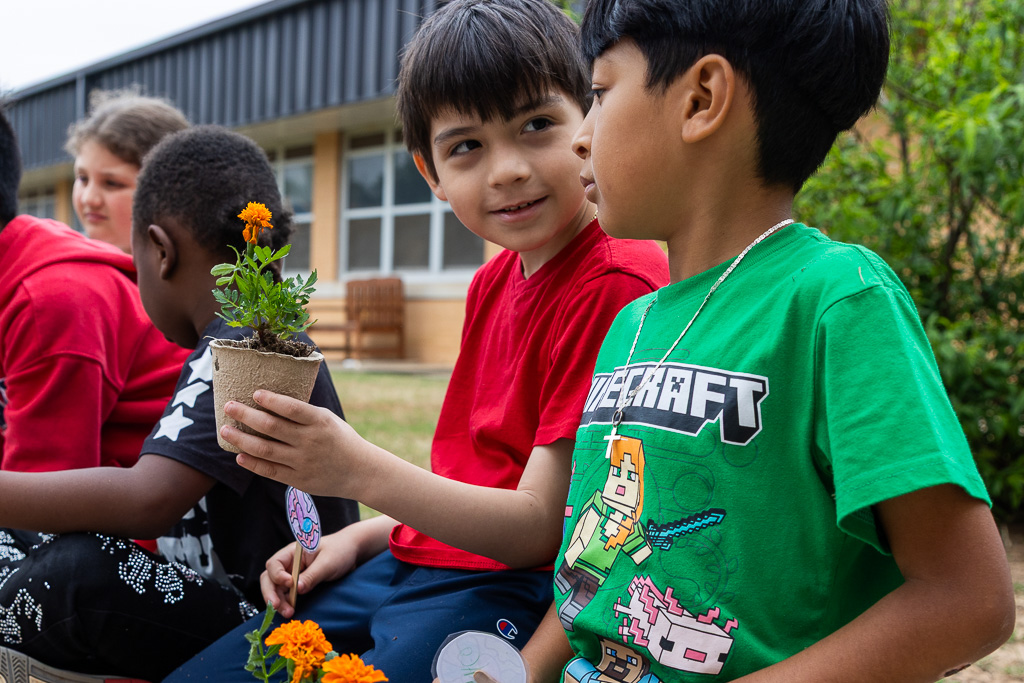 1 student holding plant, and the other student looking at the plant