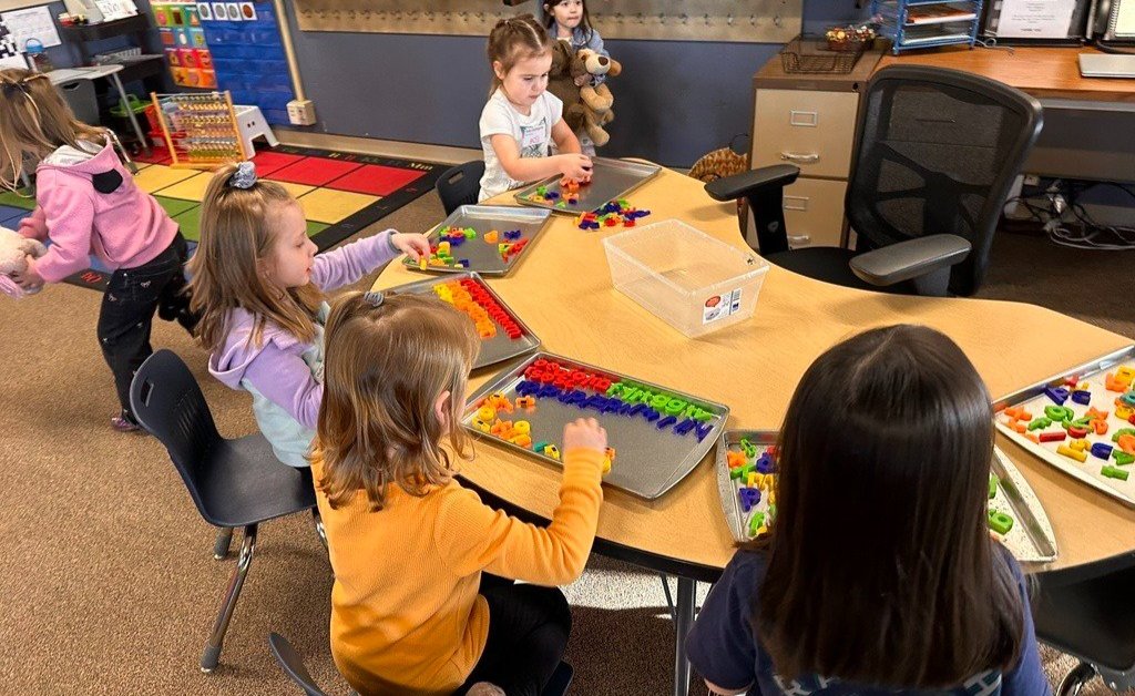future kindergarten student seated at a table playing with letters during a kindergarten orientation