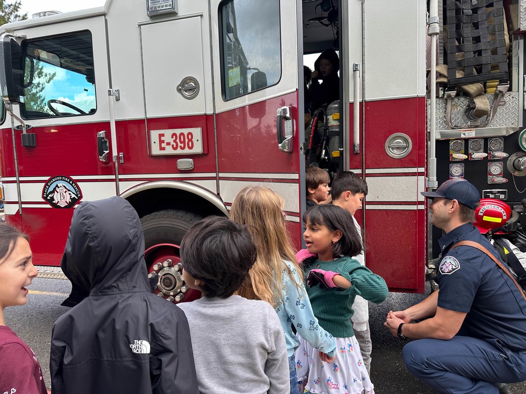 Students touring firetruck and interacting with firefighters