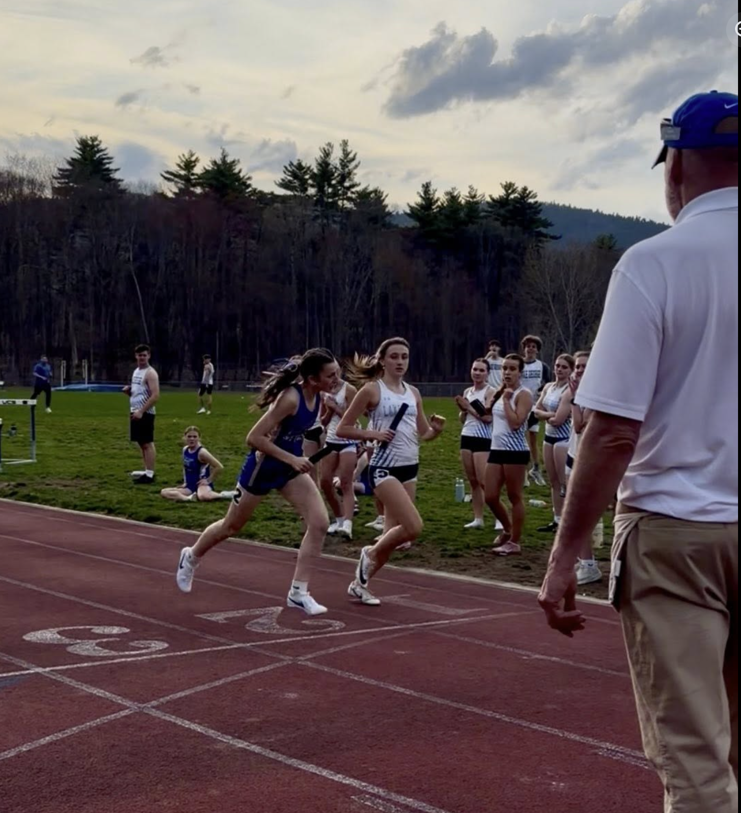 Two female track runners are at the finish line with the Granville runner winning by a nose. 