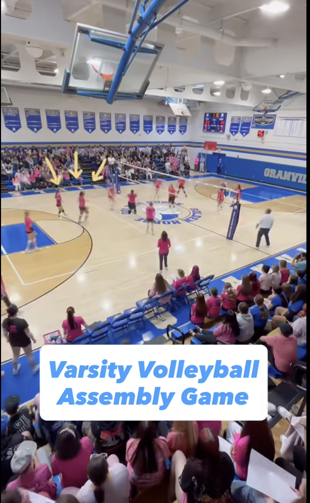 A snapshot of the varsity volleyball team in pink jerseys playing a game