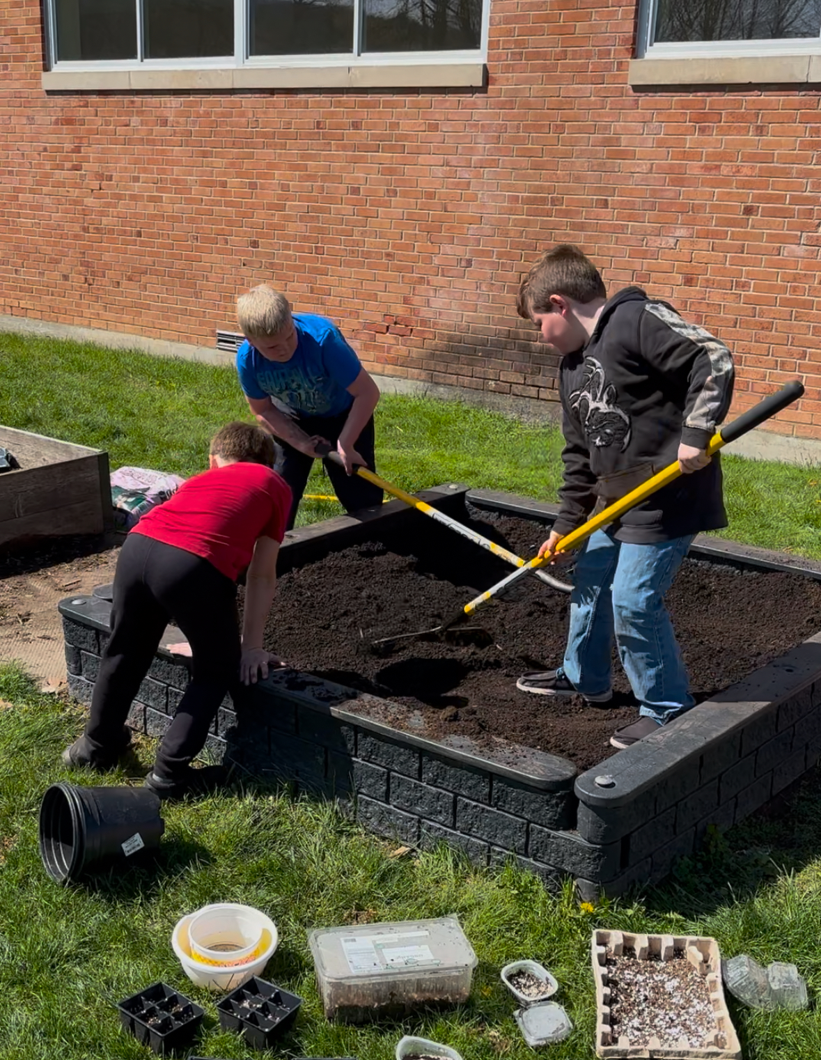 Three GES boys work on clearing the GES garden bed of weeds