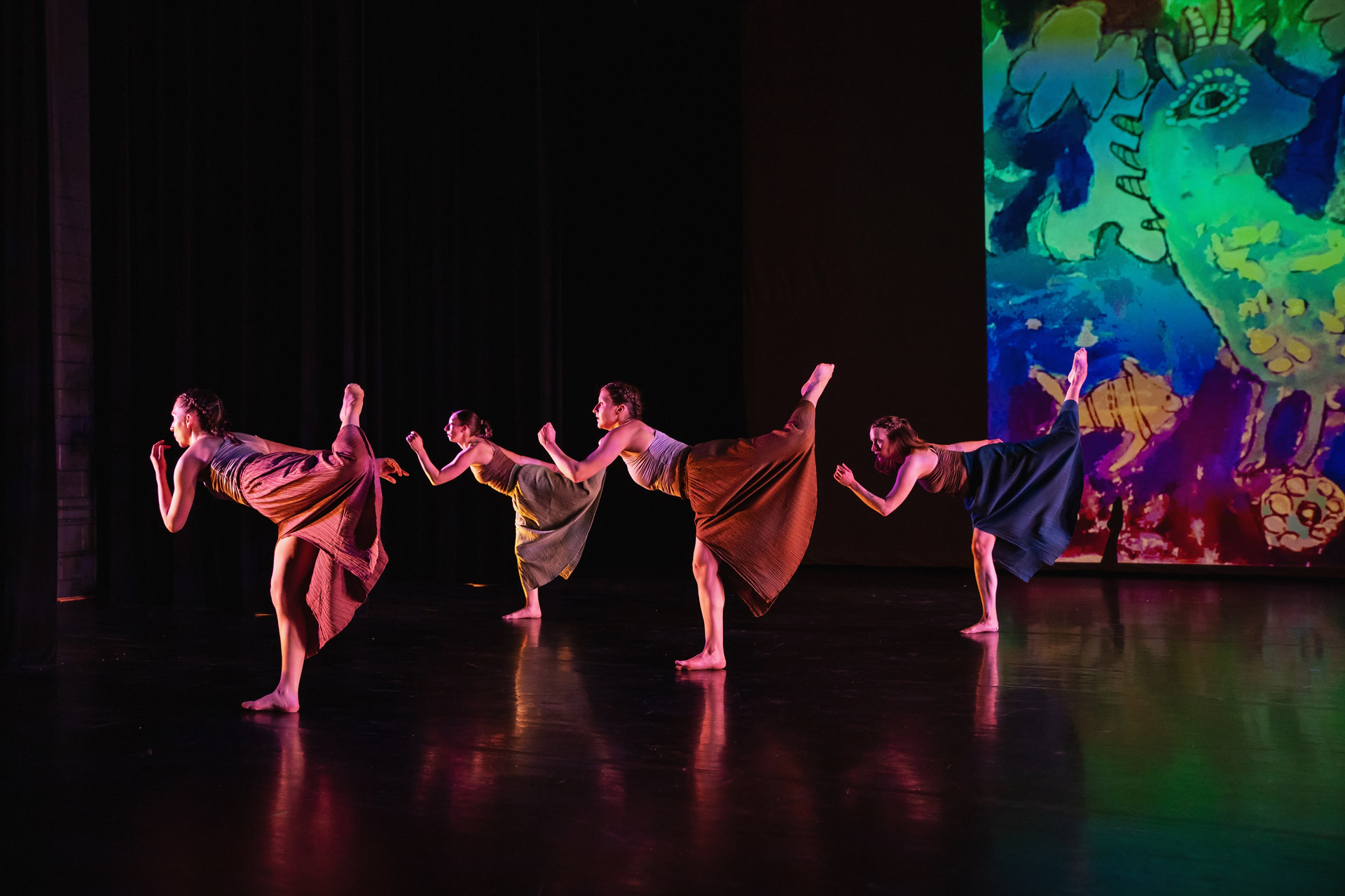 4 dancers on stage in front of large artwork