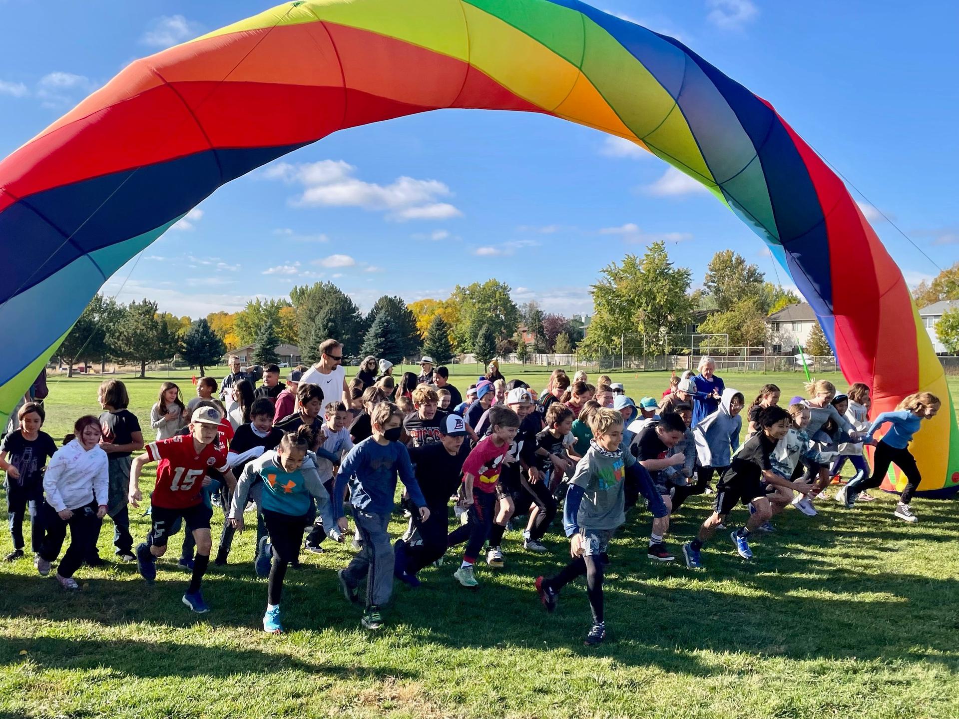 students running beneath a large inflatable rainbow