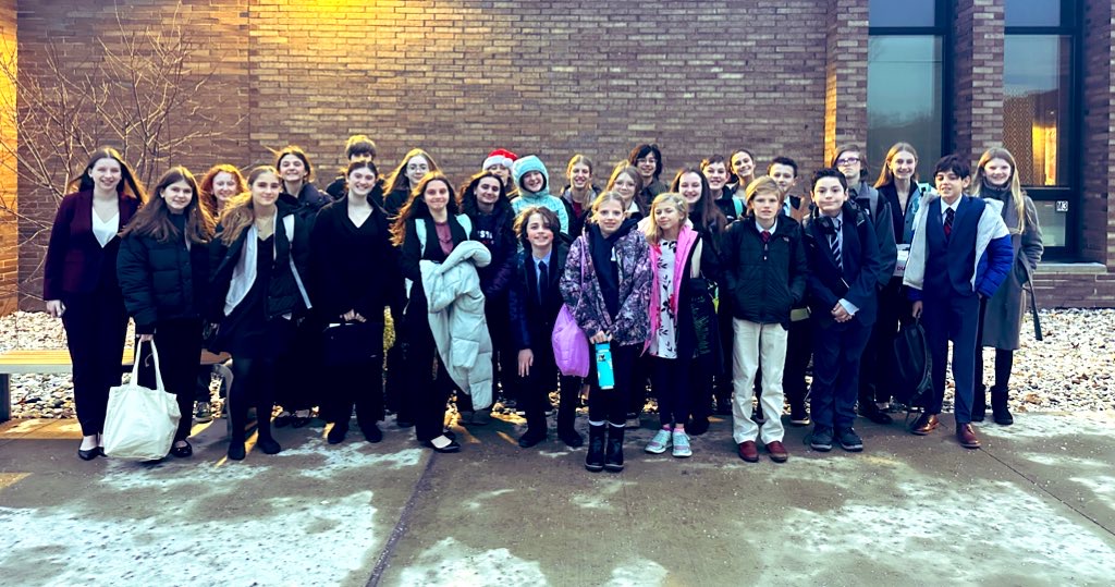 Group of students on the Speech & Debate team standing outside a building entrance.