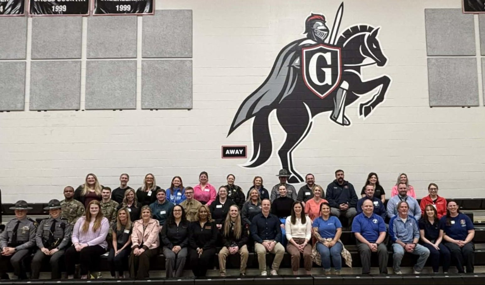 career Day Speakers sitting in bleachers with a knight logo in the wall