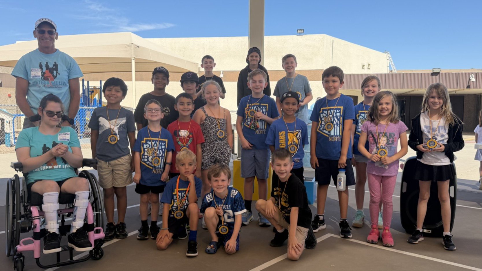 students with awards medals standing next to woman in wheelchair and adult