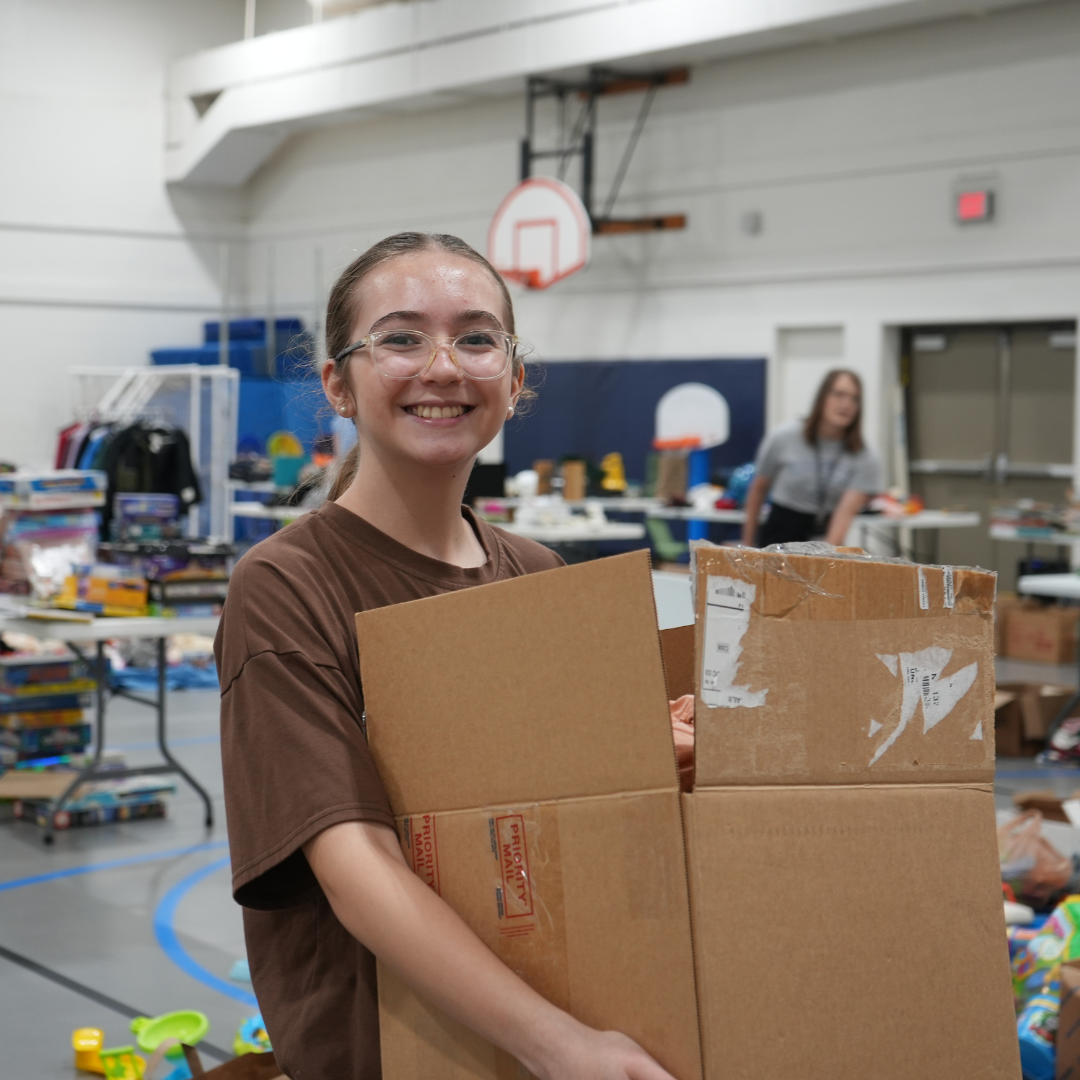 Community member holding box at garage sale 
