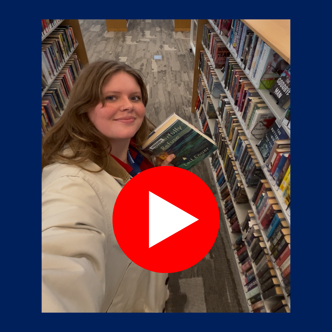 Staff member holding a copy of I Cheerfully Refuse in library