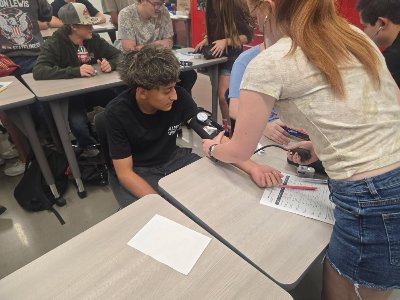 EMT student measuring vital signs on auto tech student.
