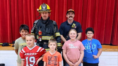 Two firefighters pose with five students