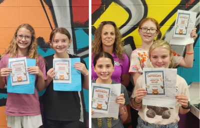 Students holding certifcates for completing summer reading program