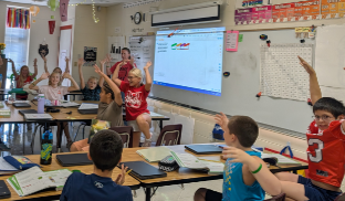 A classroom of students with arms up in celebration
