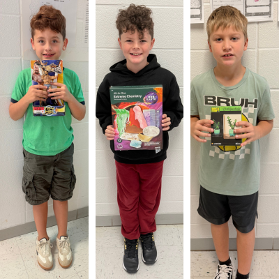 Three boys holding attendance prizes