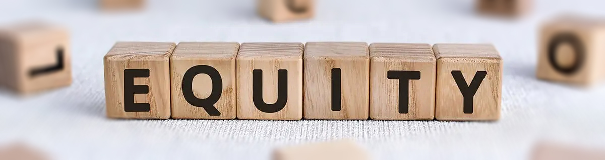 Rendered photo of alphabet blocks on a beige carpet that spell 'EQUITY'. There are blurred out blocks in the background and foreground.