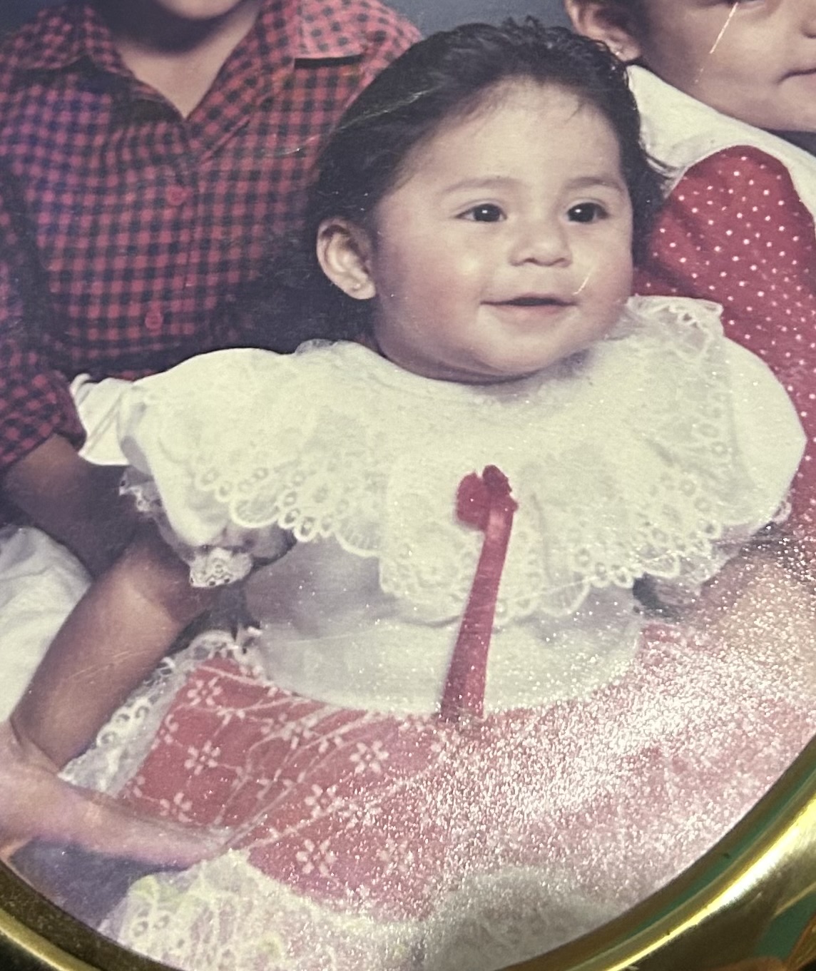 Pictured: an infant wearing a white and red dress.