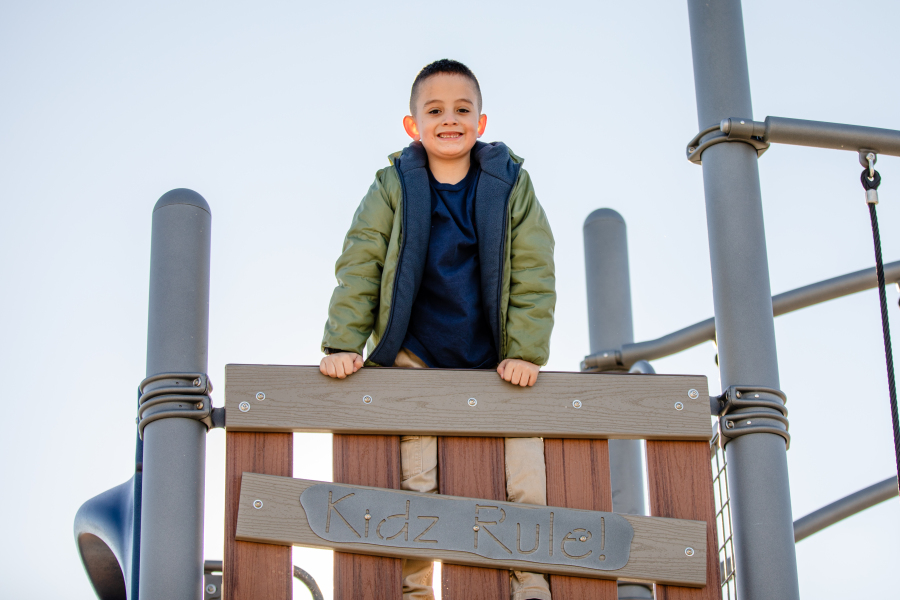 A student smiles for a photo while playing on the playground.