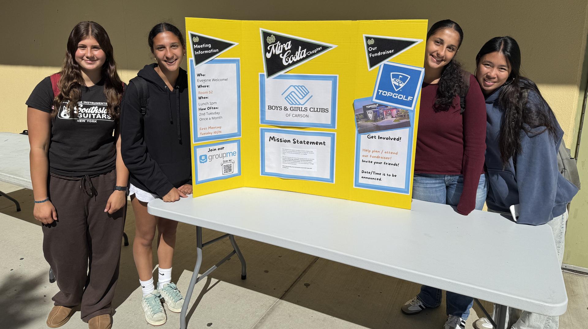students at table with sign