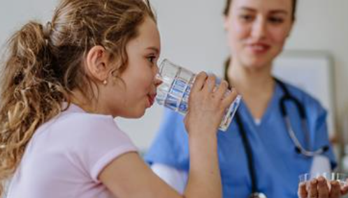 Child drinking water in clinic with nurse
