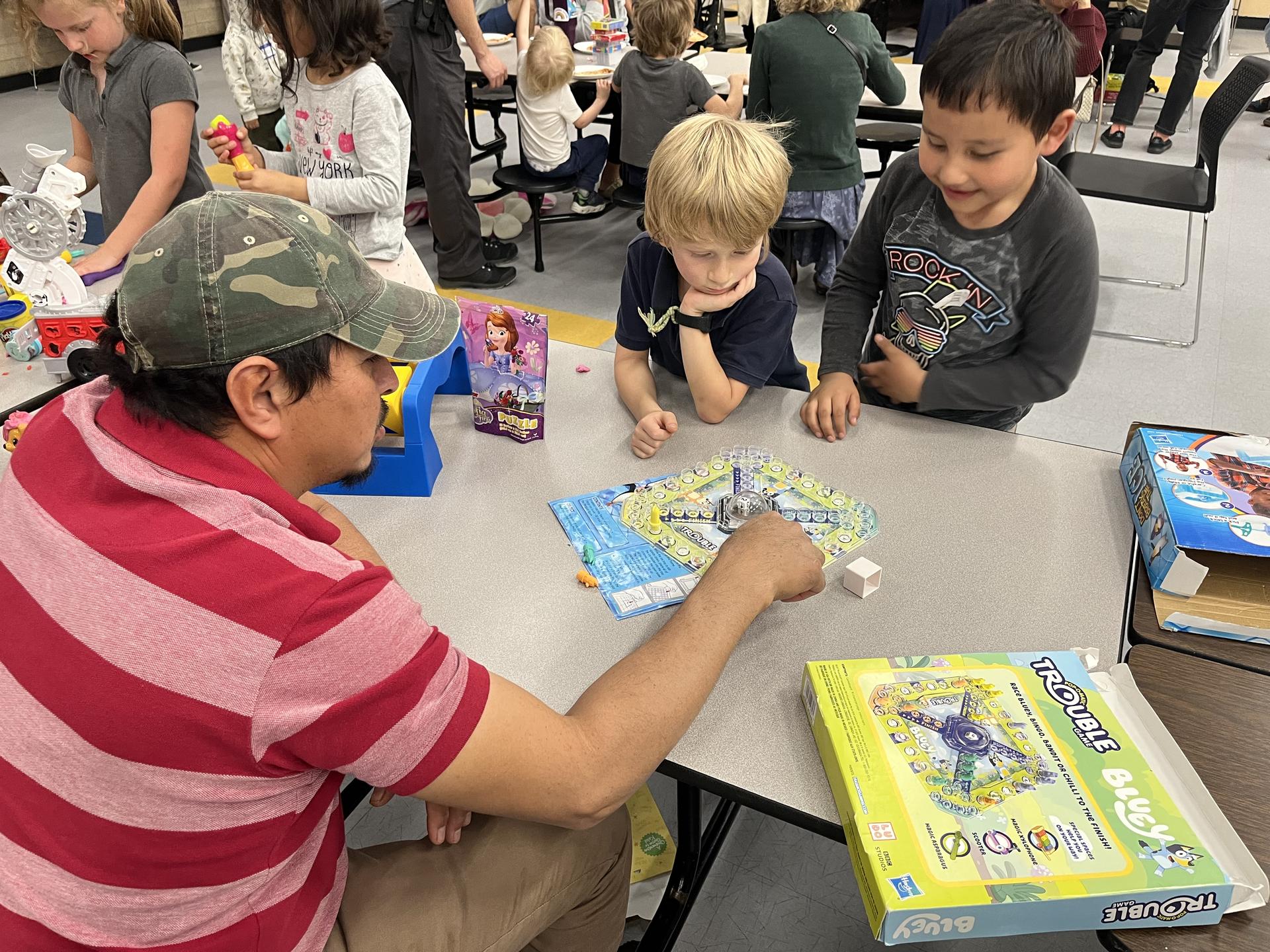 Students playing a board game with one father