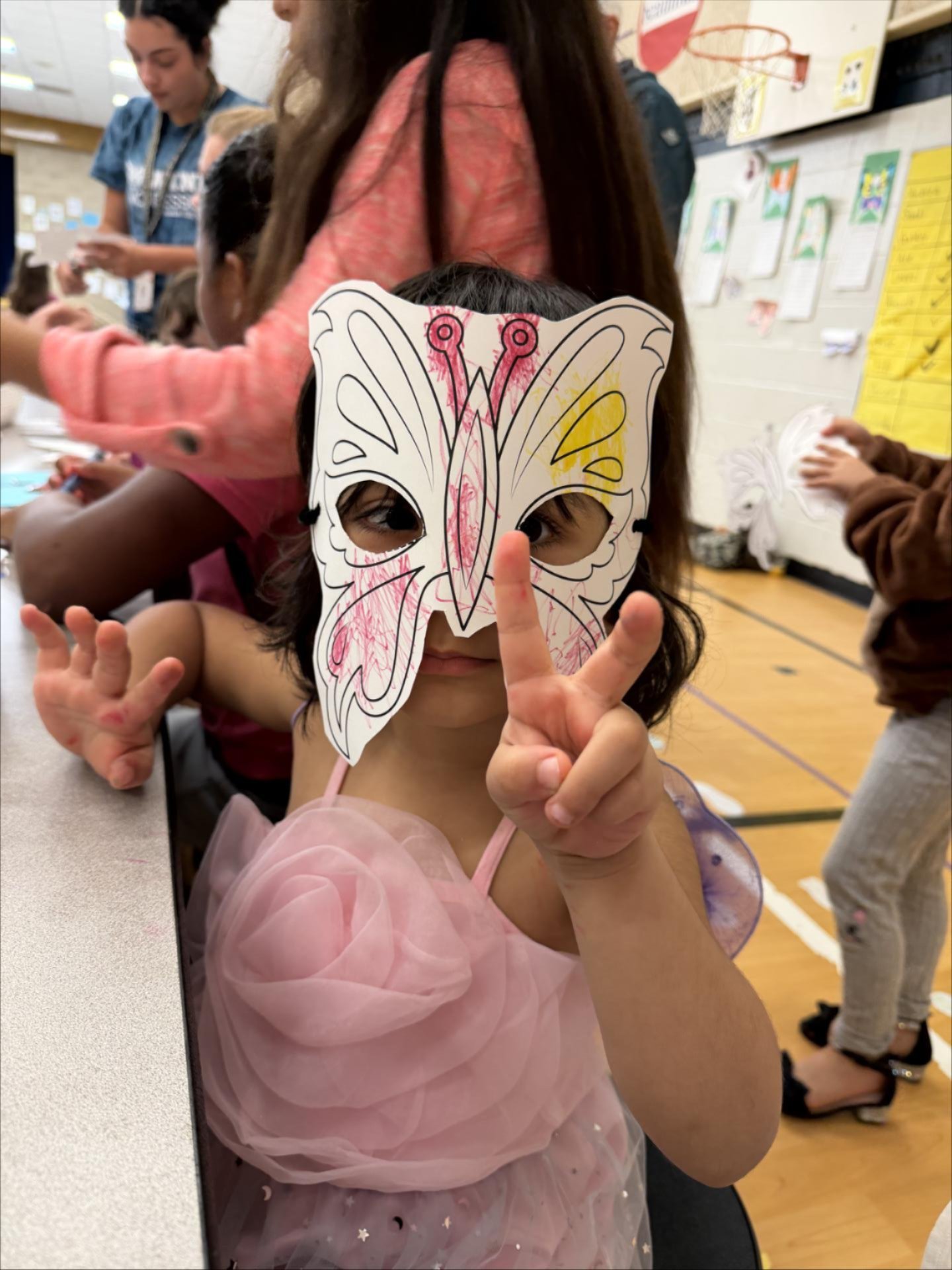Child with butterfly mask holding a peace sign