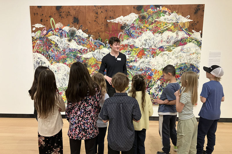 Students looking at a large art display with a tour guide talking to them