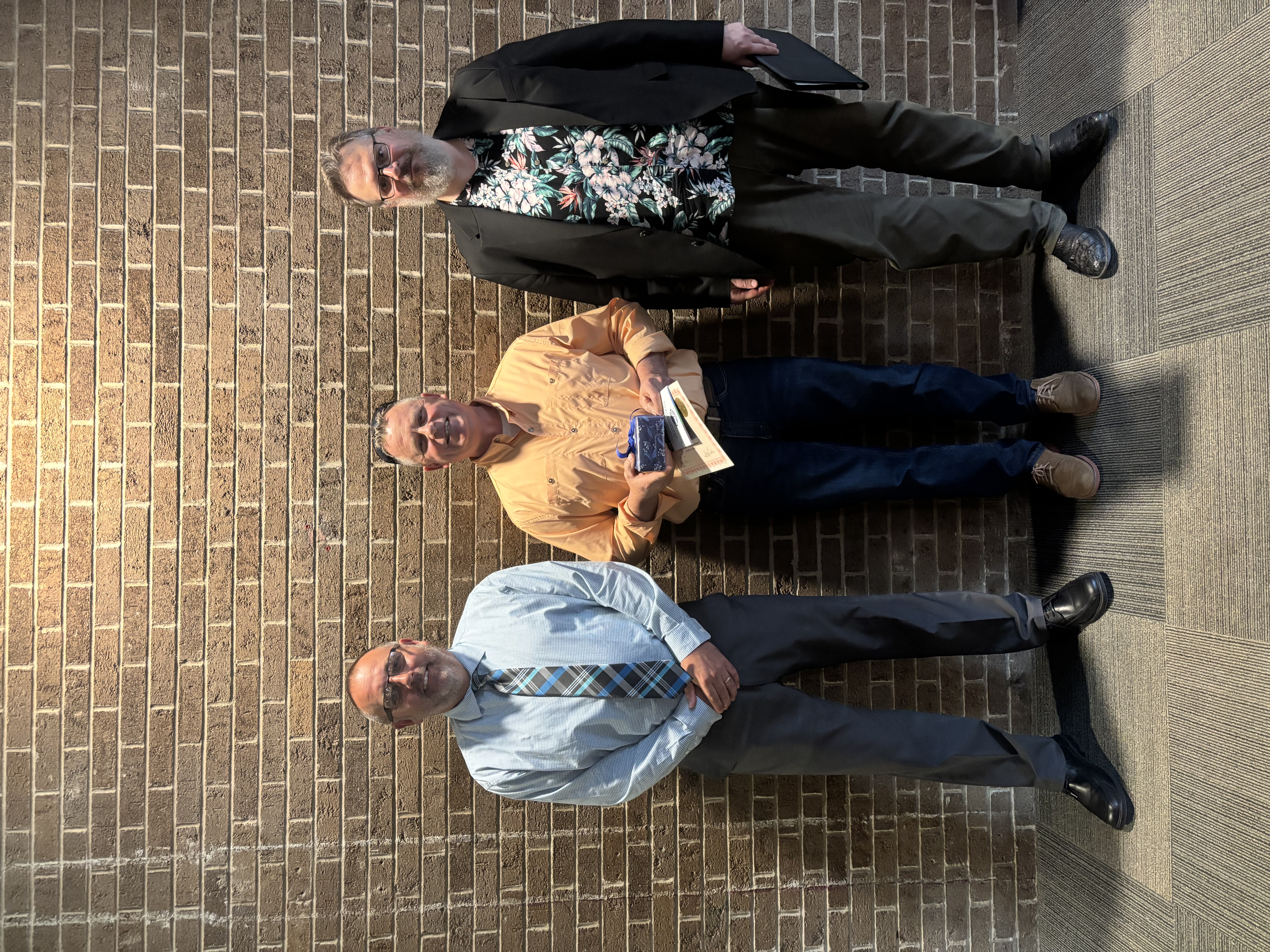 Three people posing in front of lobby wall