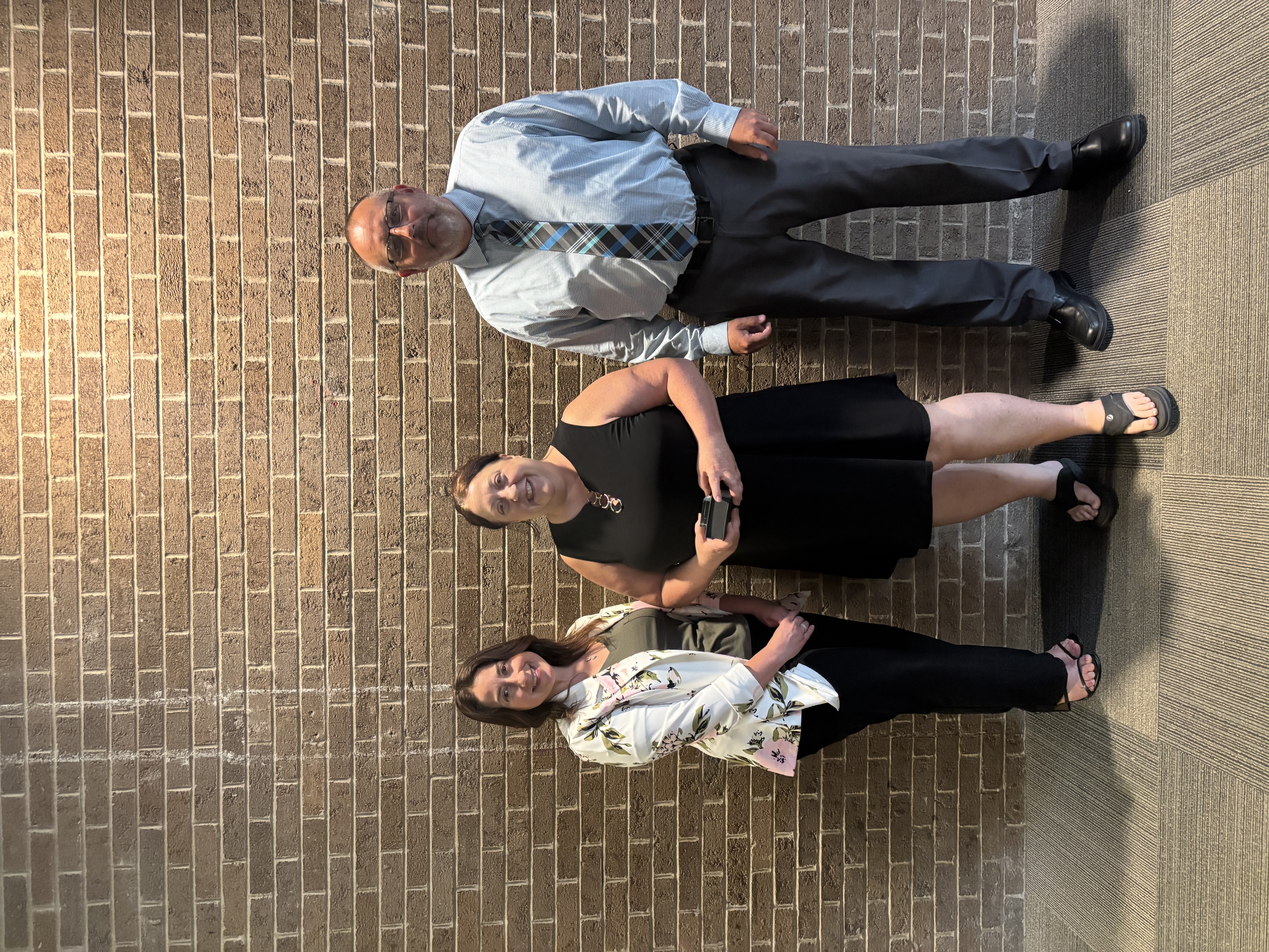 Three people posing by lobby wall