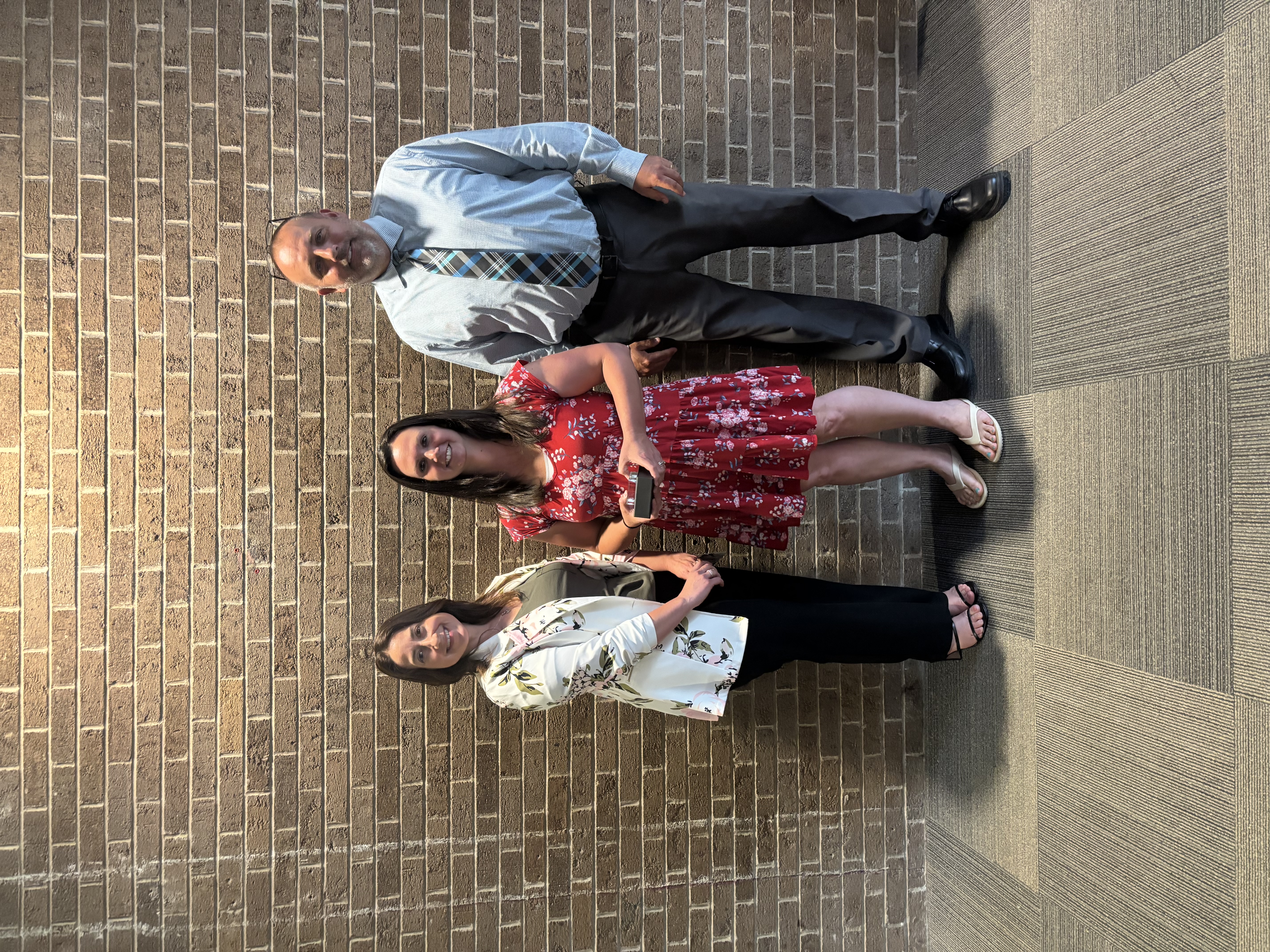 Three people posing by lobby wall