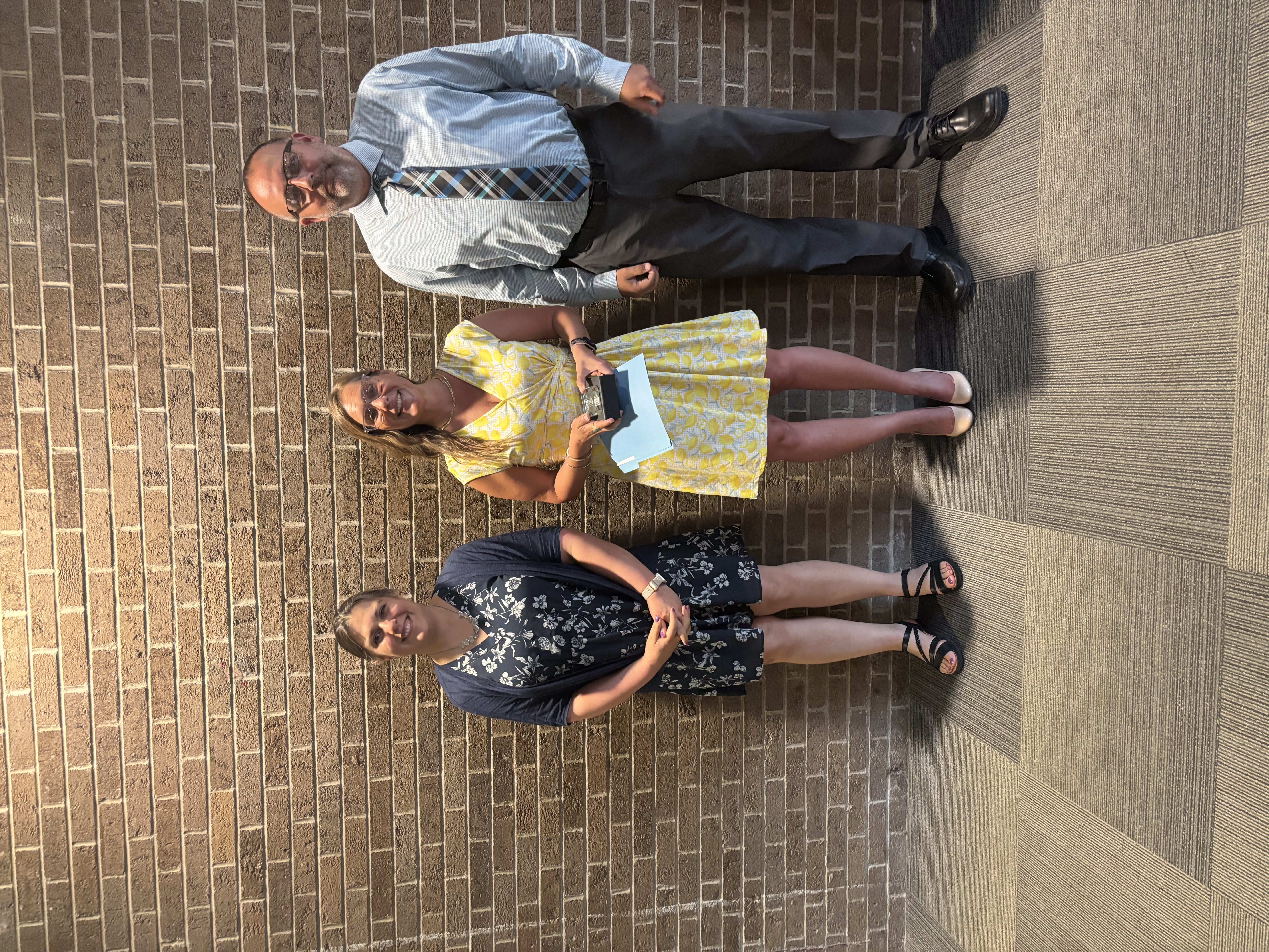 Three people posing by lobby wall