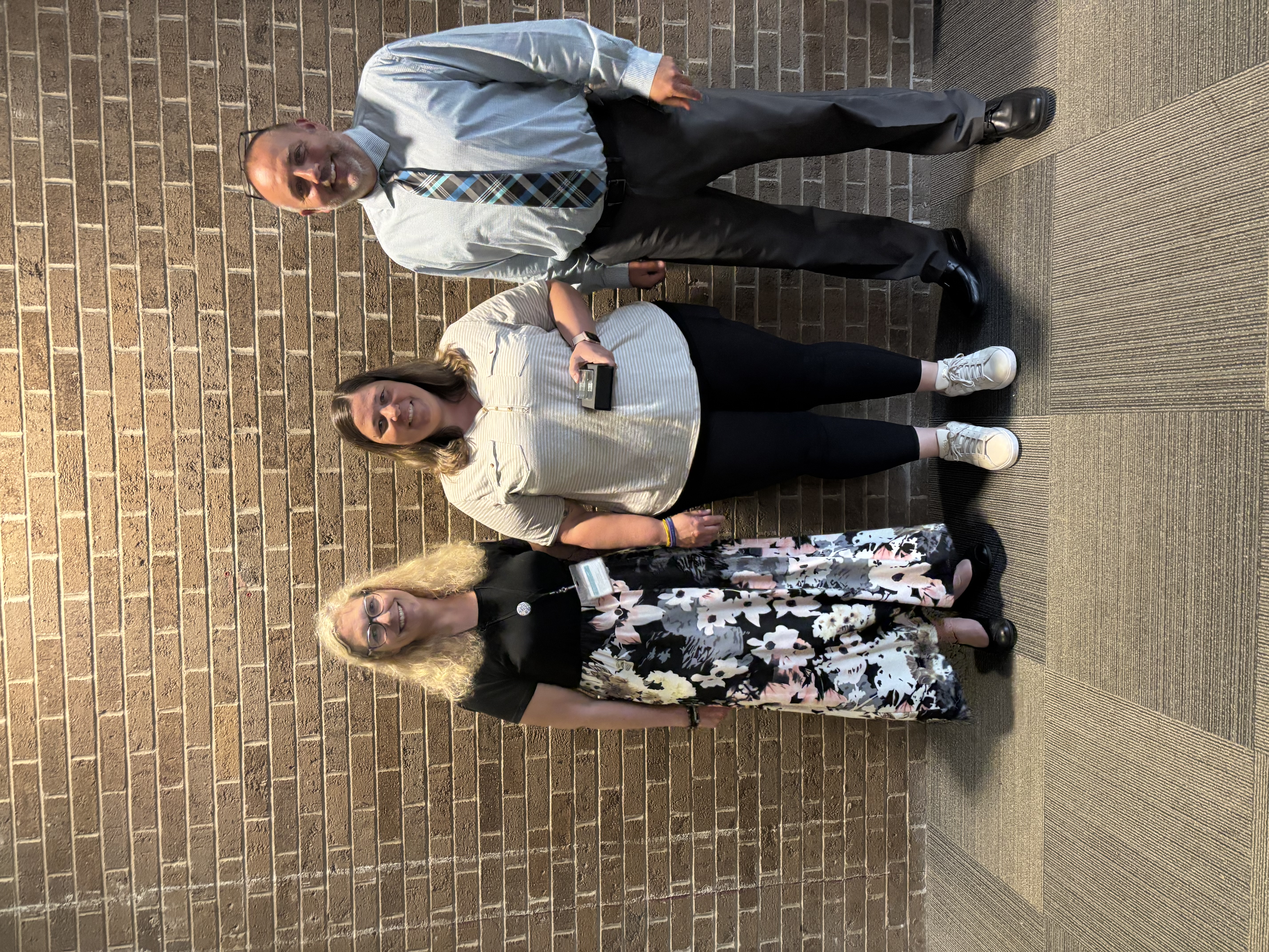 Three people posing by lobby wall