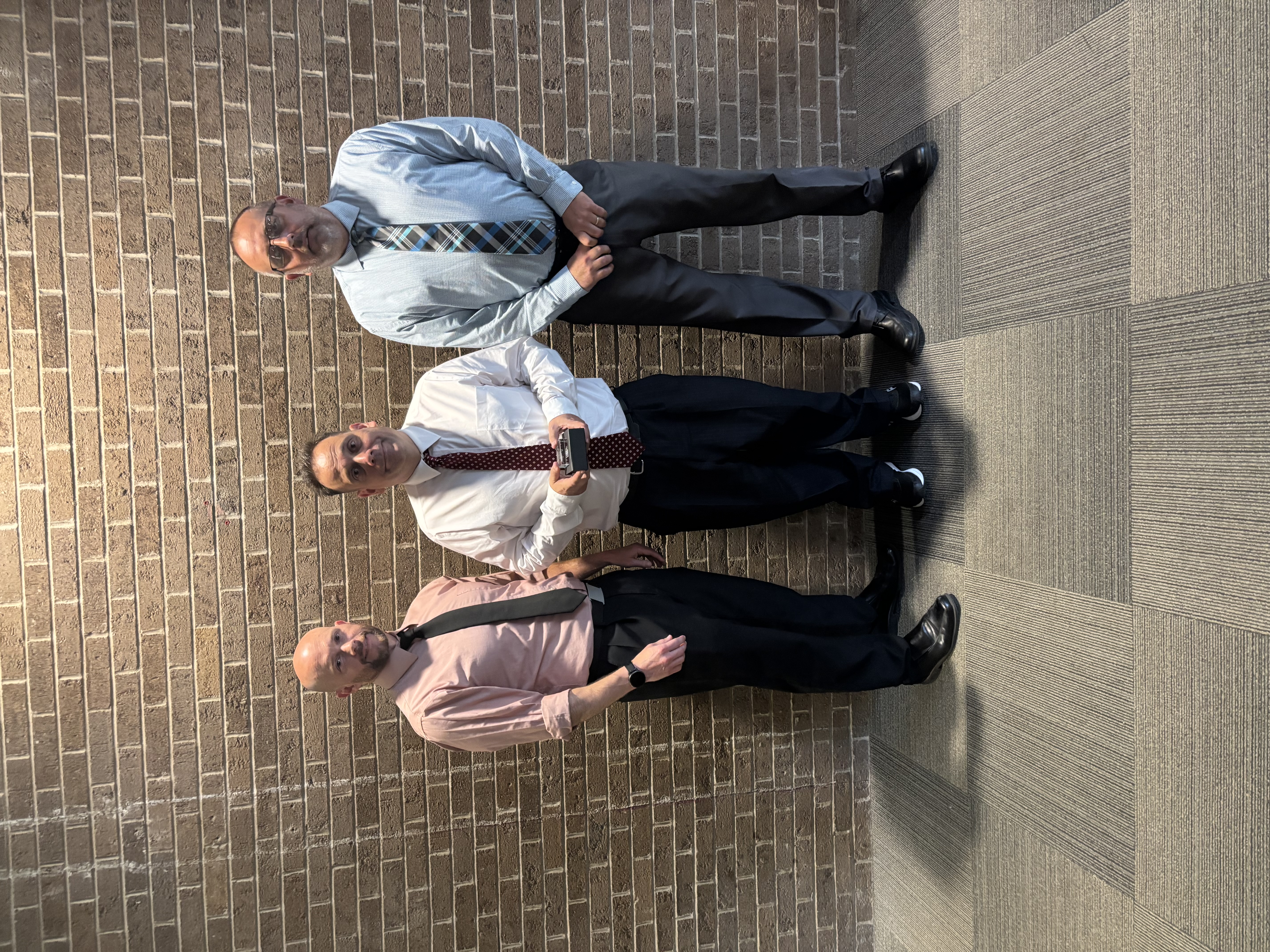 Three people posing by lobby wall
