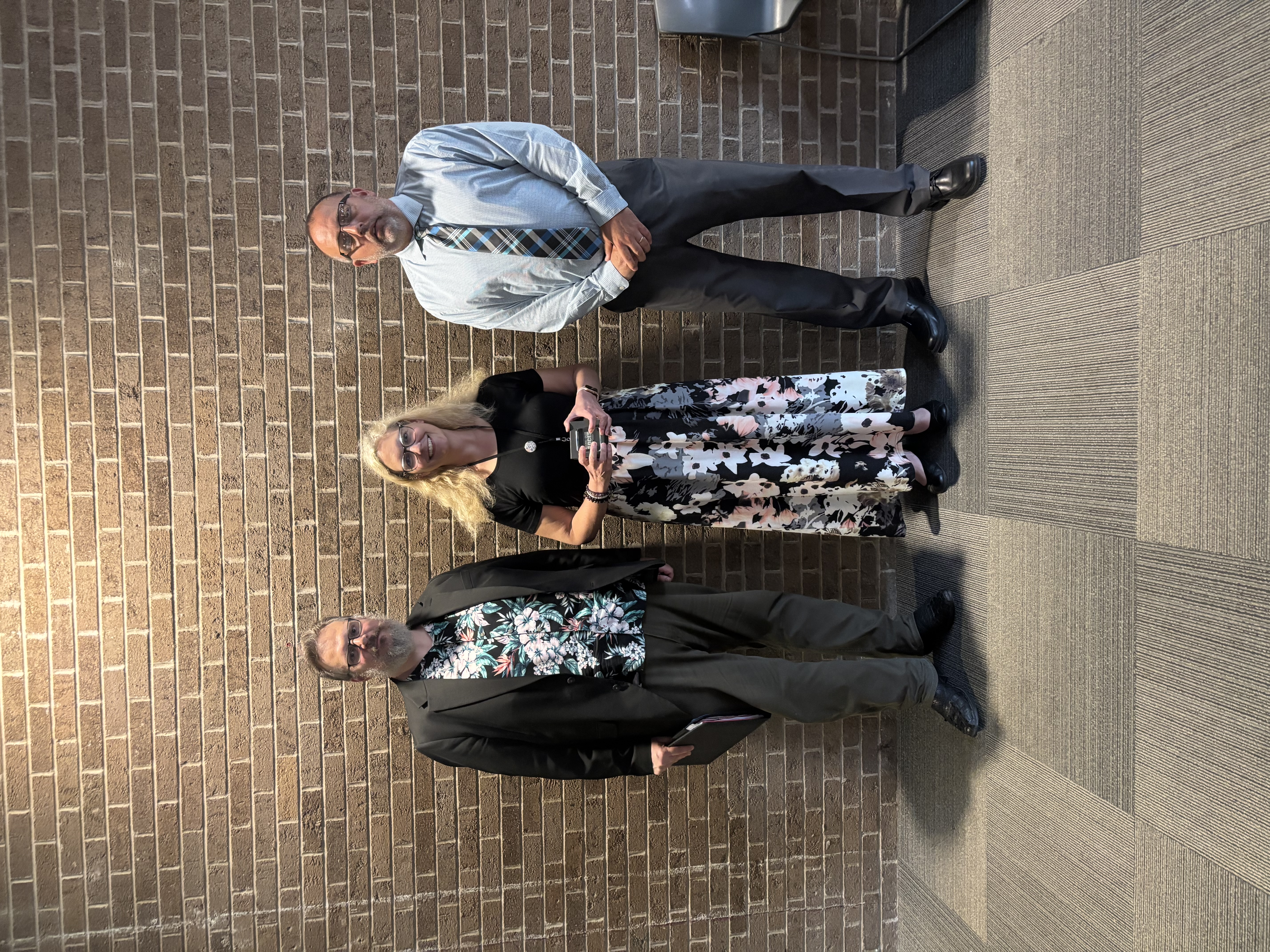 Three people posing by lobby wall