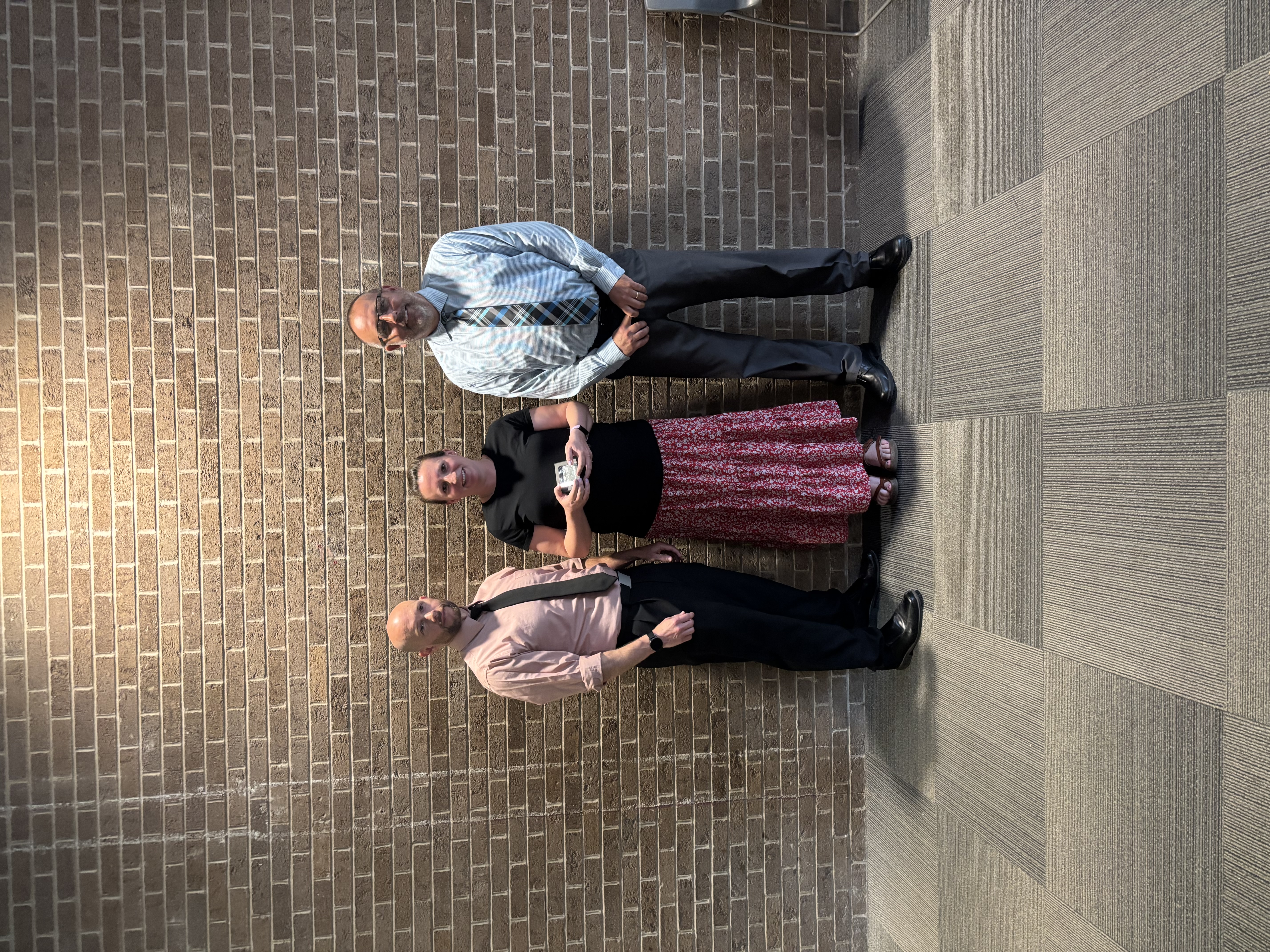 Three people posing by lobby wall