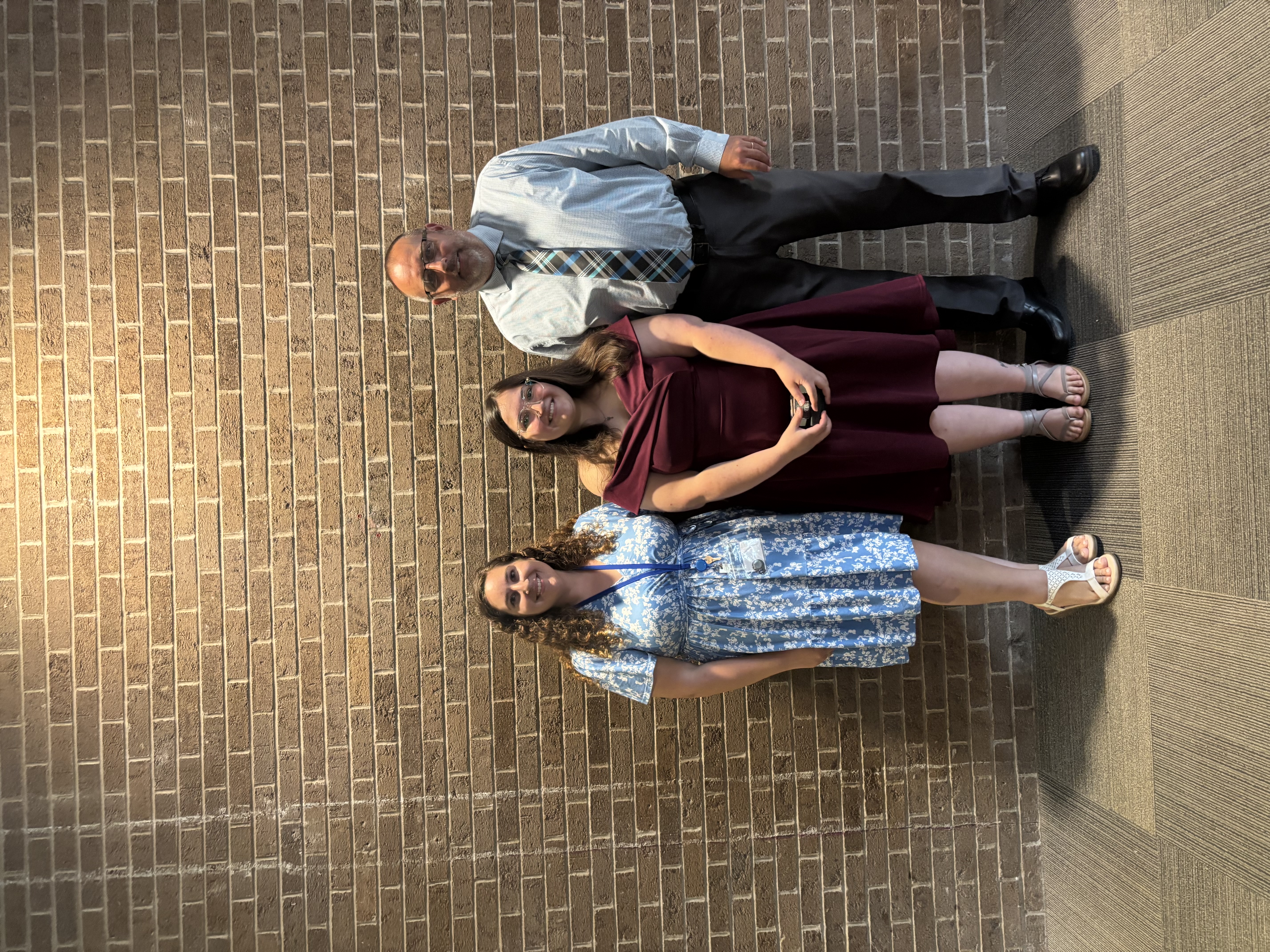 Three people posing by lobby wall