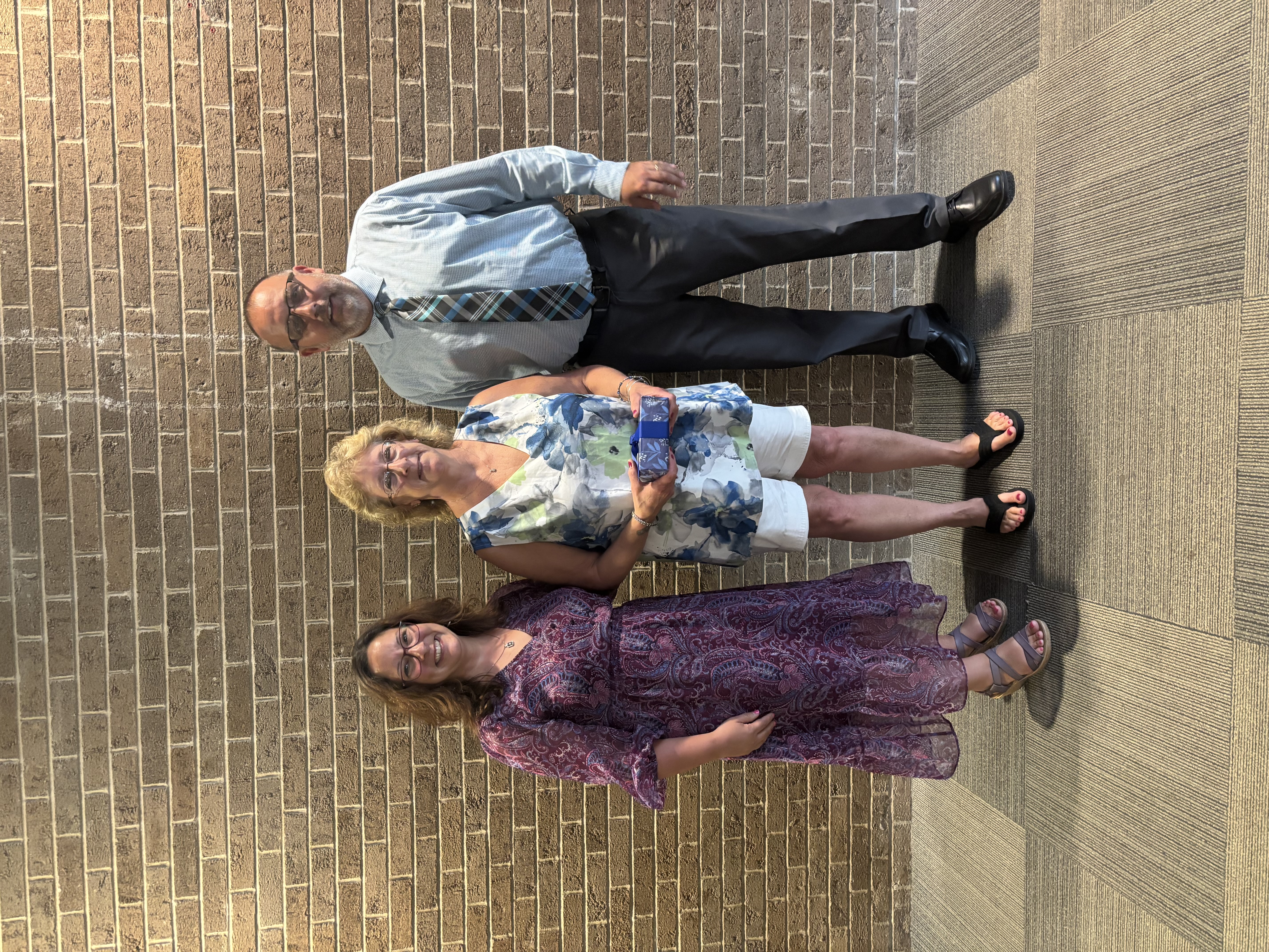 Three people posing in front of lobby wall