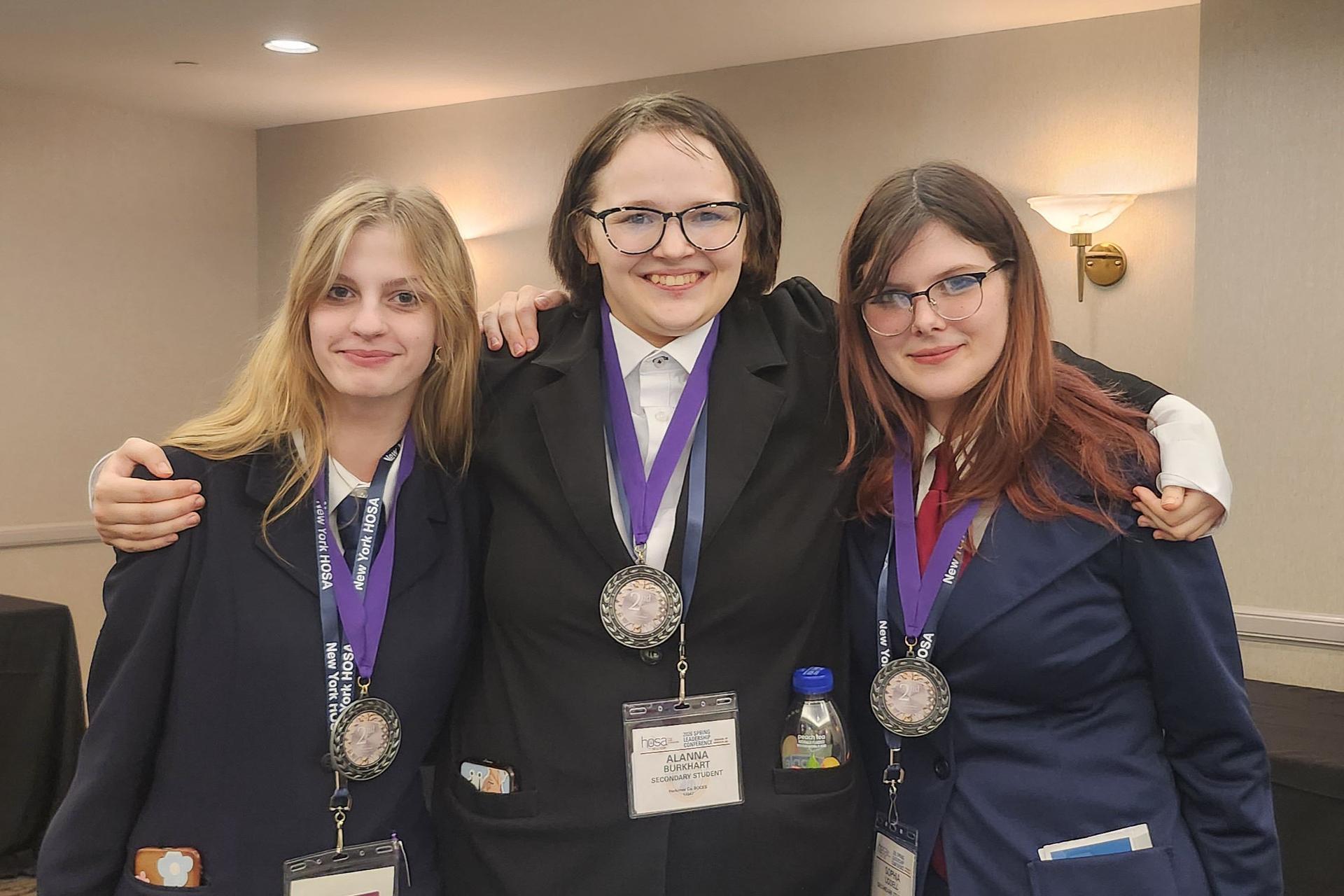 Three Health Science Careers students posing together with medals on