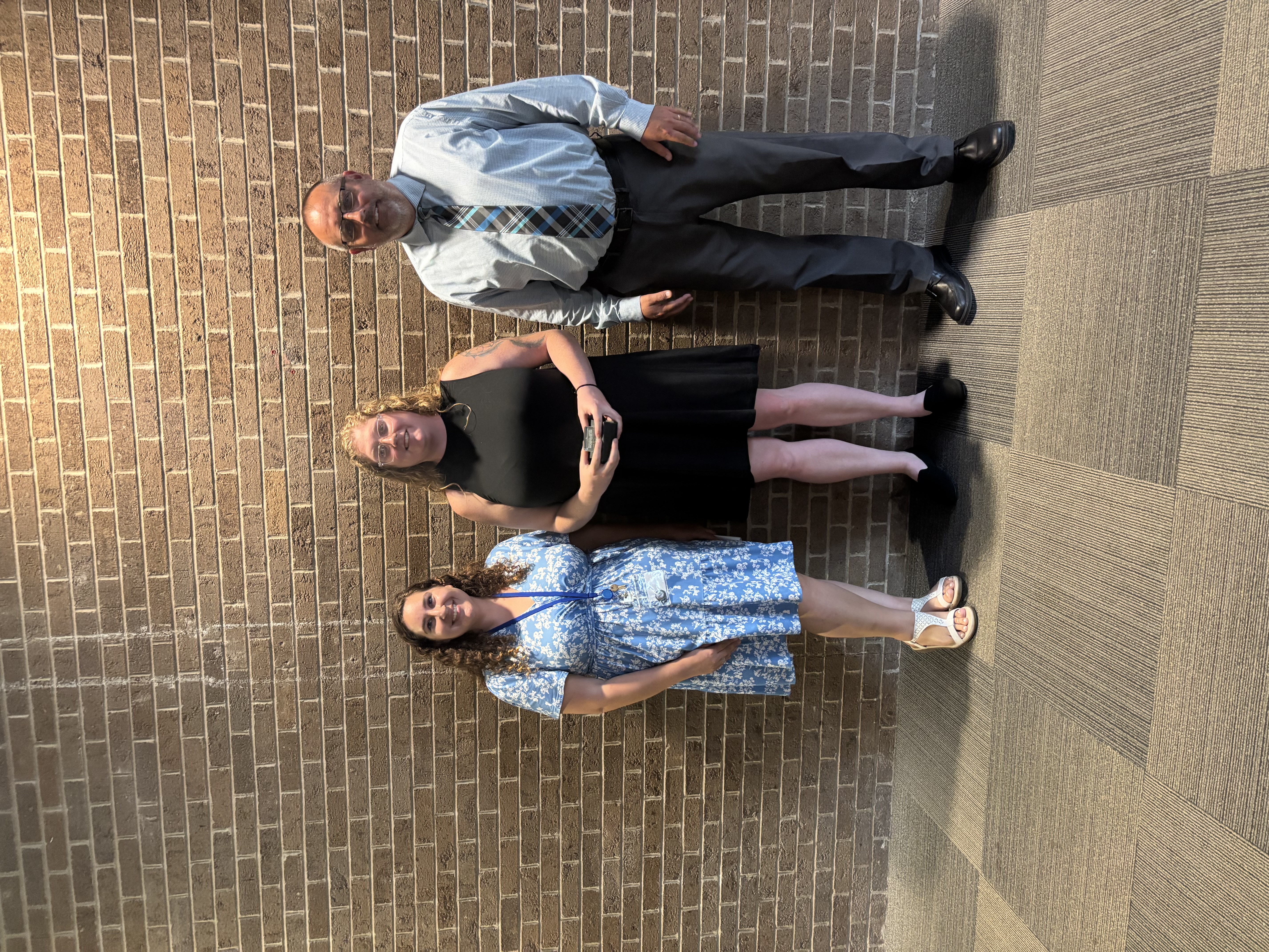 Three people posing by lobby wall