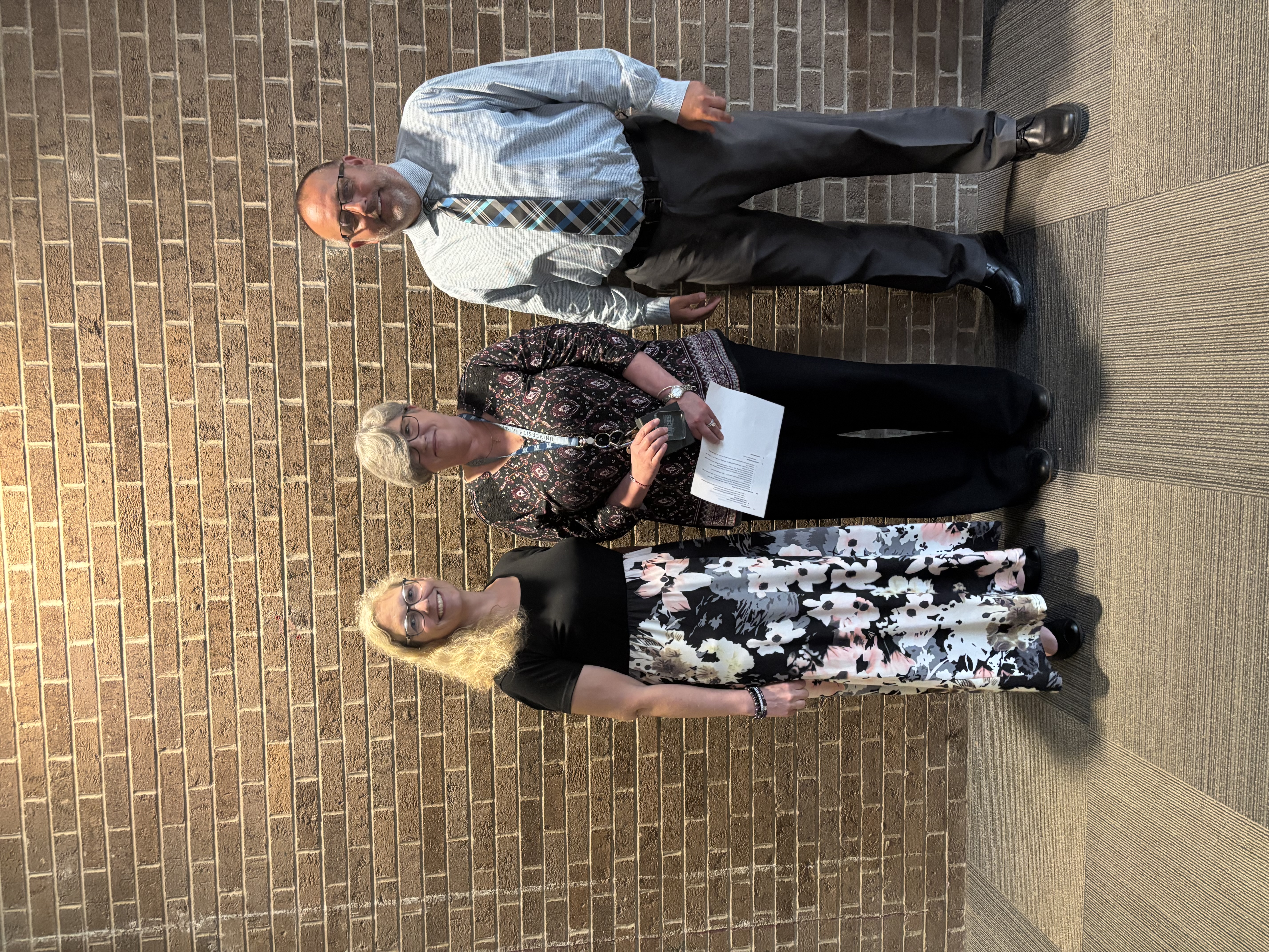 Three people posing by lobby wall