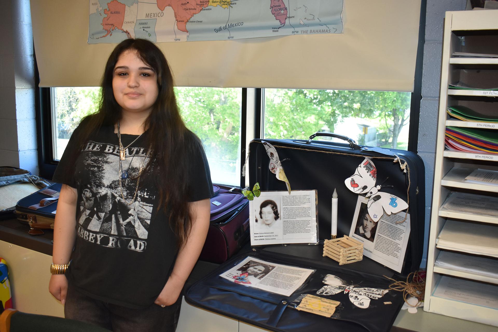 Student posed by suitcase Holocaust project