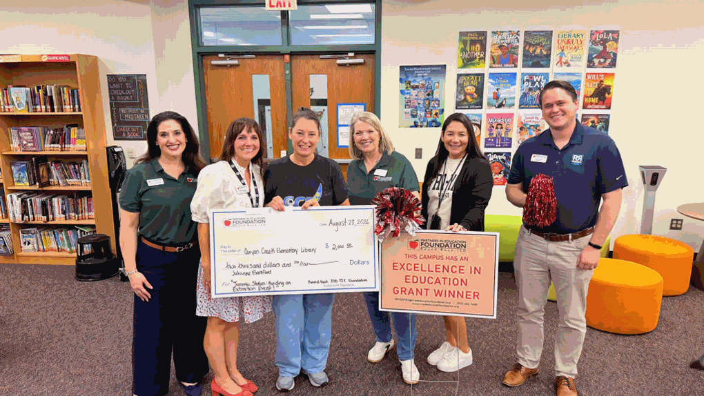 librarian holding large grant check